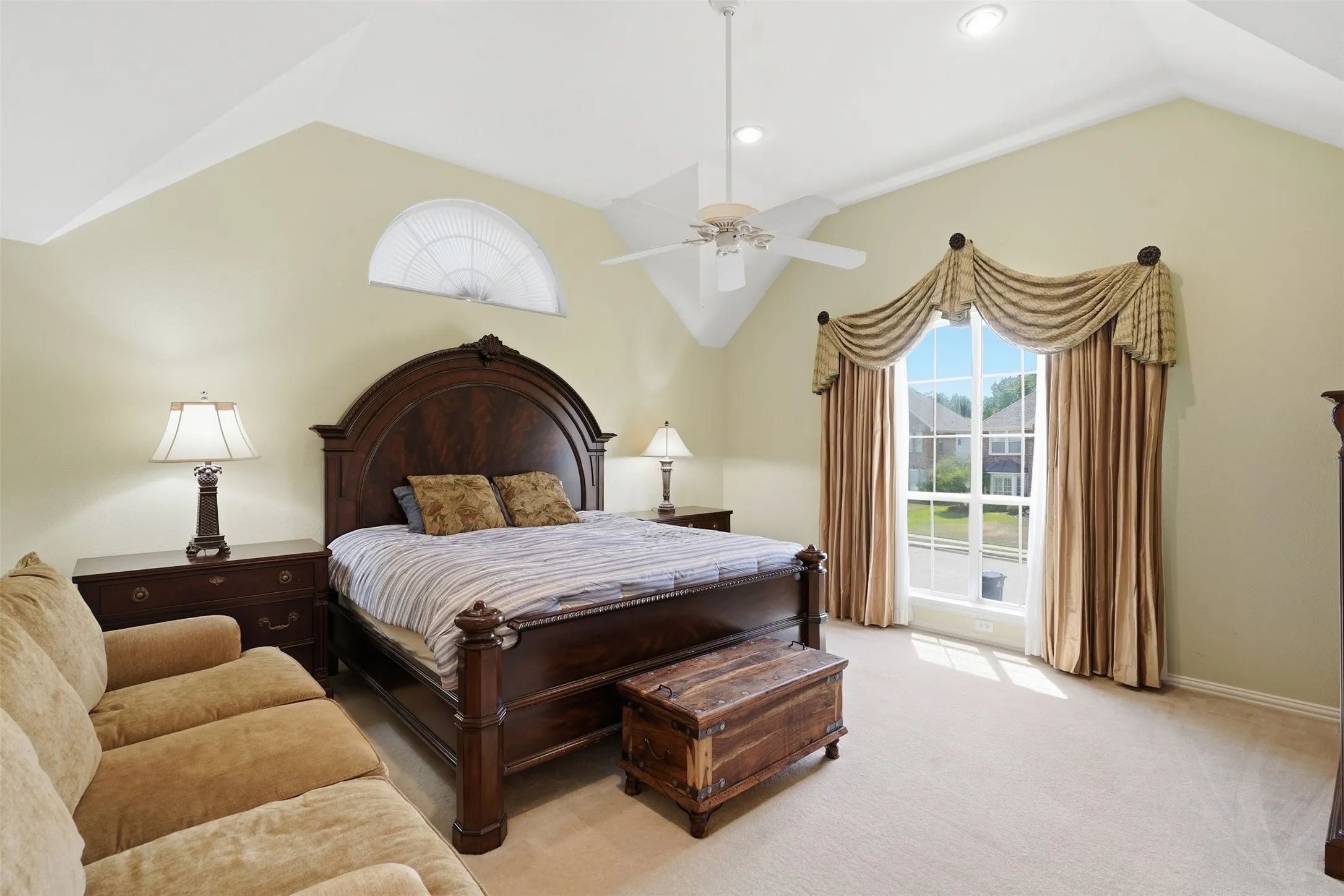 Spacious room featuring vaulted ceilings, a large arched window, a ceiling fan with integrated lighting, and recessed lighting