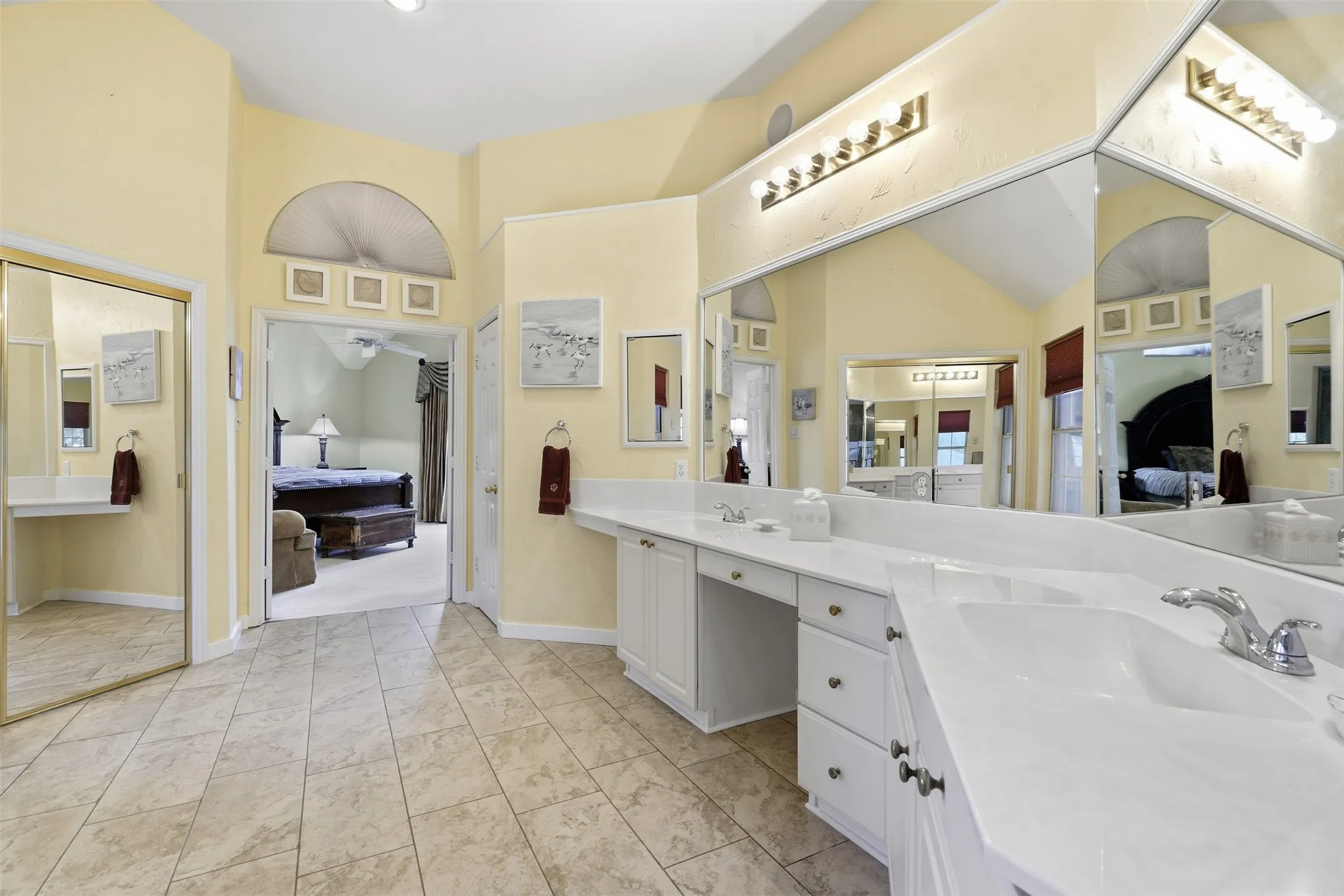 Spacious bathroom featuring an expansive vanity with double sinks, white cabinetry, and wall-mounted mirrors