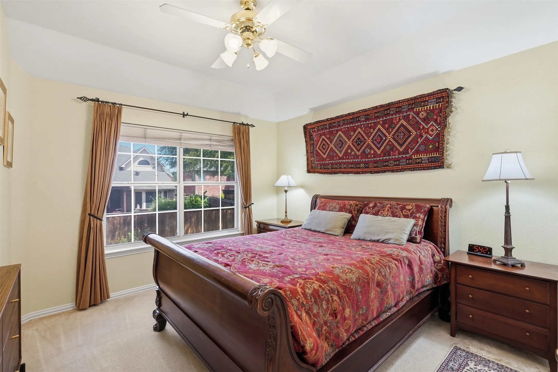 Carpeted room featuring a large window with white muntins and a ceiling fan with integrated lighting