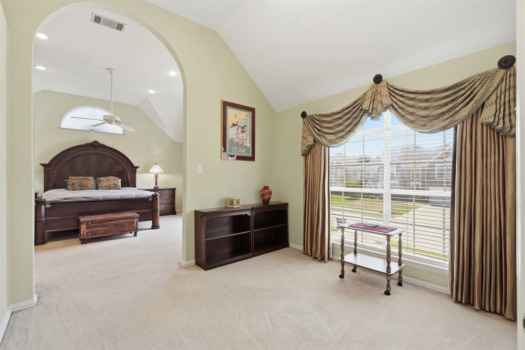 Archway entry to a carpeted room featuring a vaulted ceiling with recessed lighting and a ceiling fan