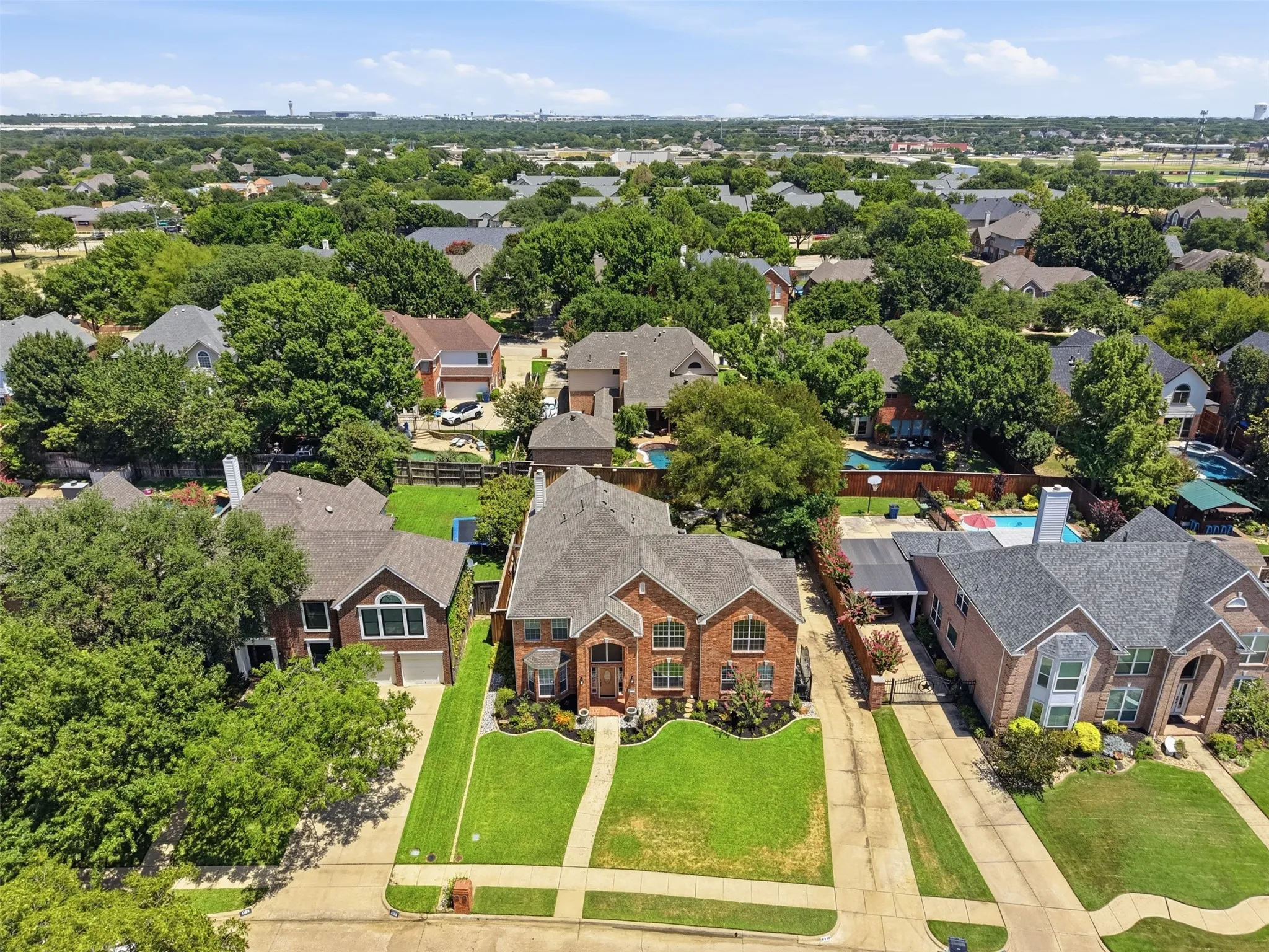 Traditional-style brick residence featuring a multi-gabled roofline, mature landscaping, and a concrete driveway