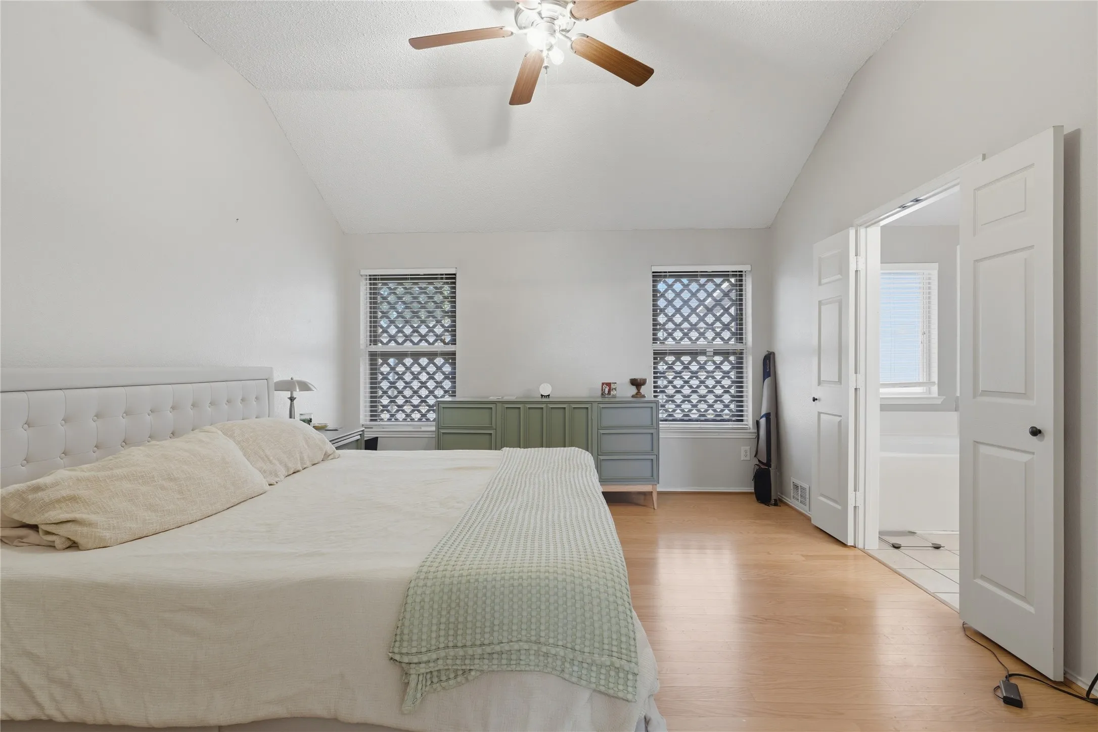 Vaulted ceiling with a ceiling fan, light wood-finish flooring, and window blinds