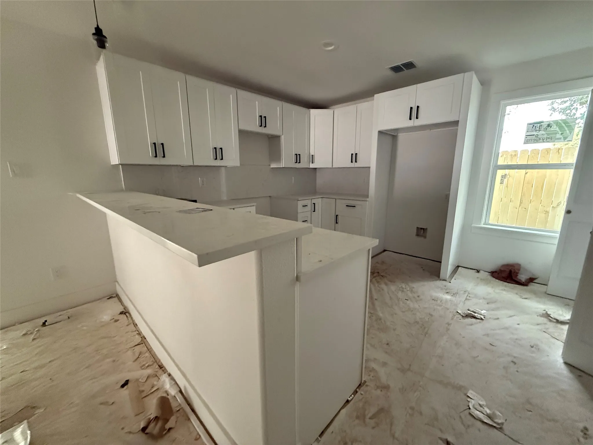 Kitchen featuring white shaker cabinetry, light-toned countertops, and a built-in breakfast bar