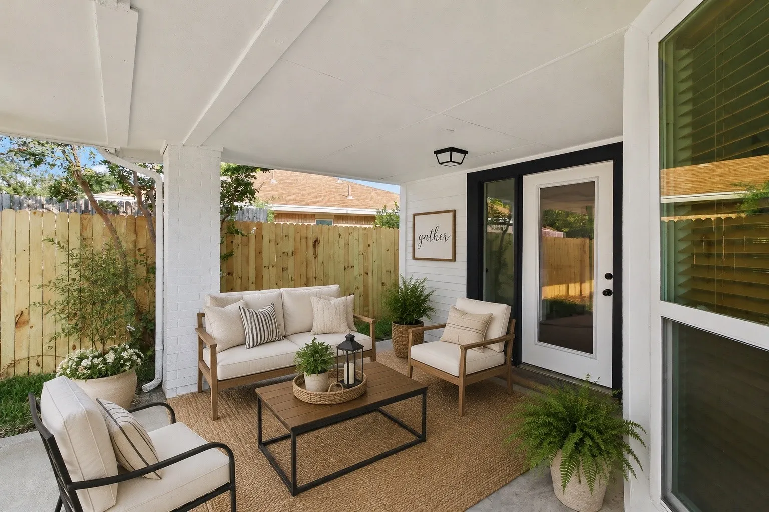 Covered patio retreat featuring comfortable seating areas, a wood-finish coffee table, cork-look flooring, and black-framed glass doors opening to the home