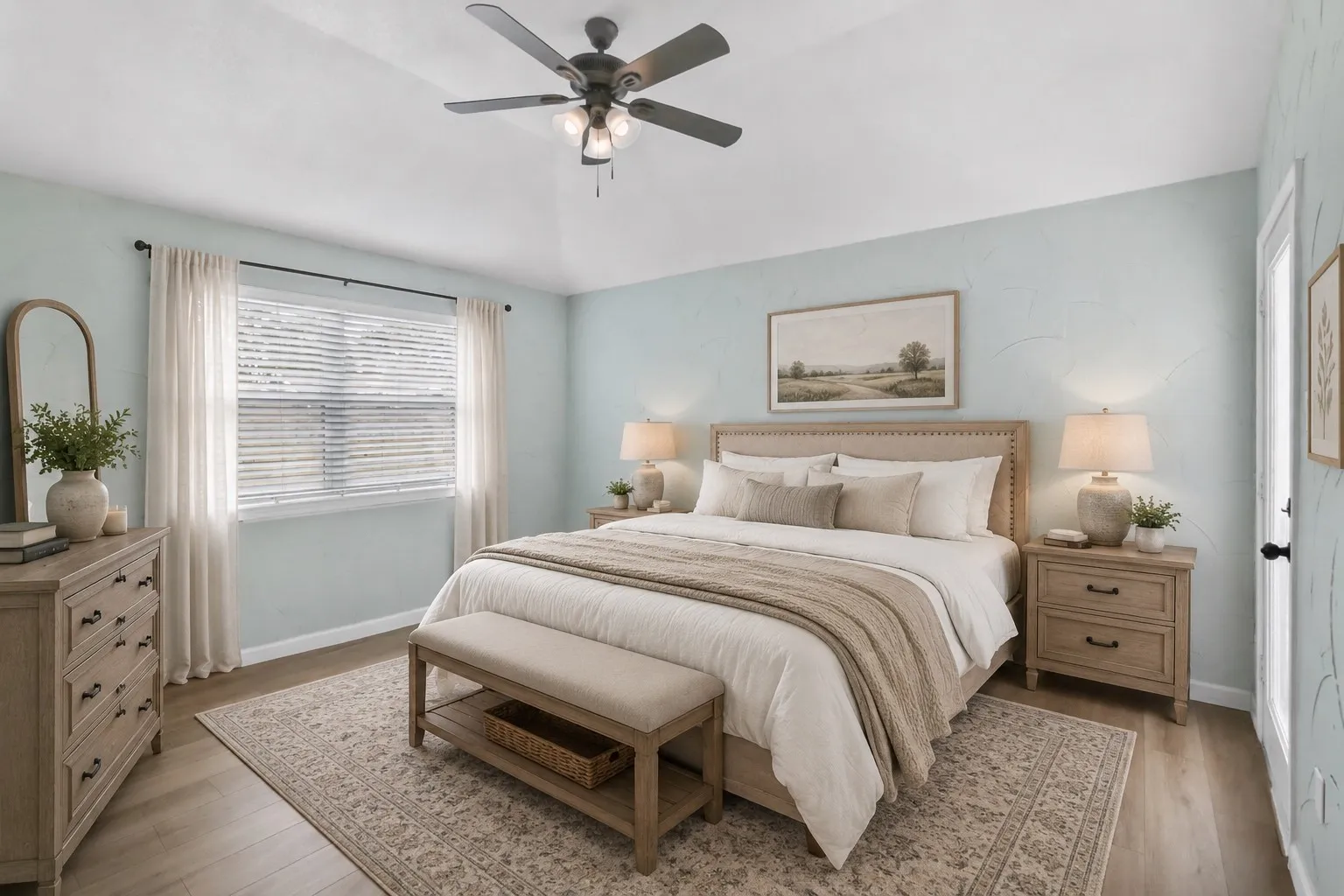 Primary bedroom featuring light blue walls, wood-finish flooring, and a ceiling fan with integrated lighting