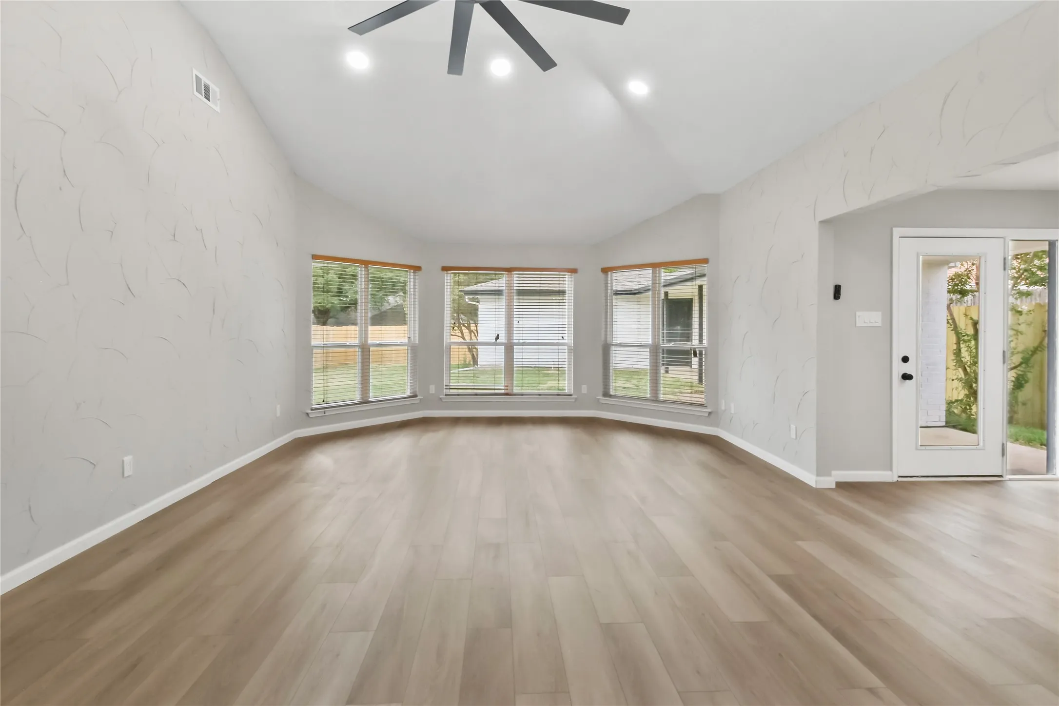 Vaulted ceilings, wood-finish flooring, recessed lighting, and a contemporary ceiling fan