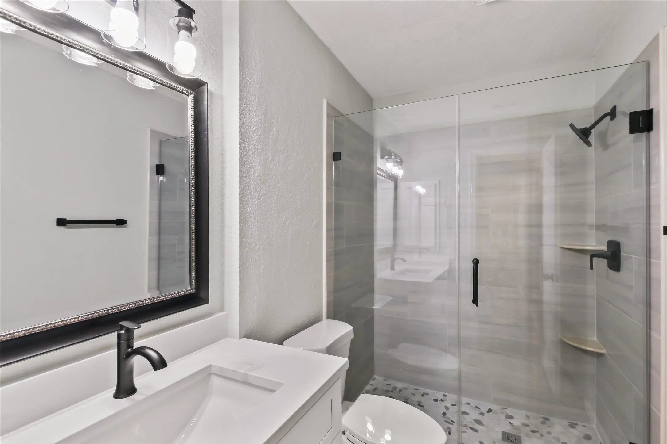 White vanity with an integrated sink, matte black faucet, and a large framed mirror