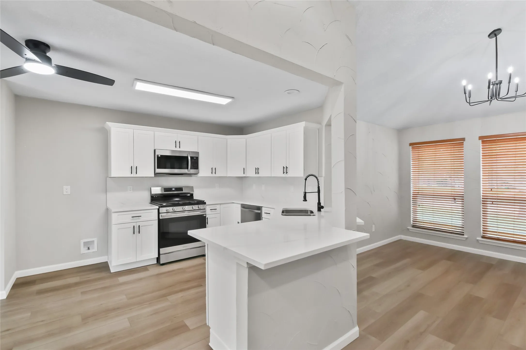 Modern kitchen featuring white cabinetry with stainless steel appliances, a gas range, and a large quartz-topped island with seating
