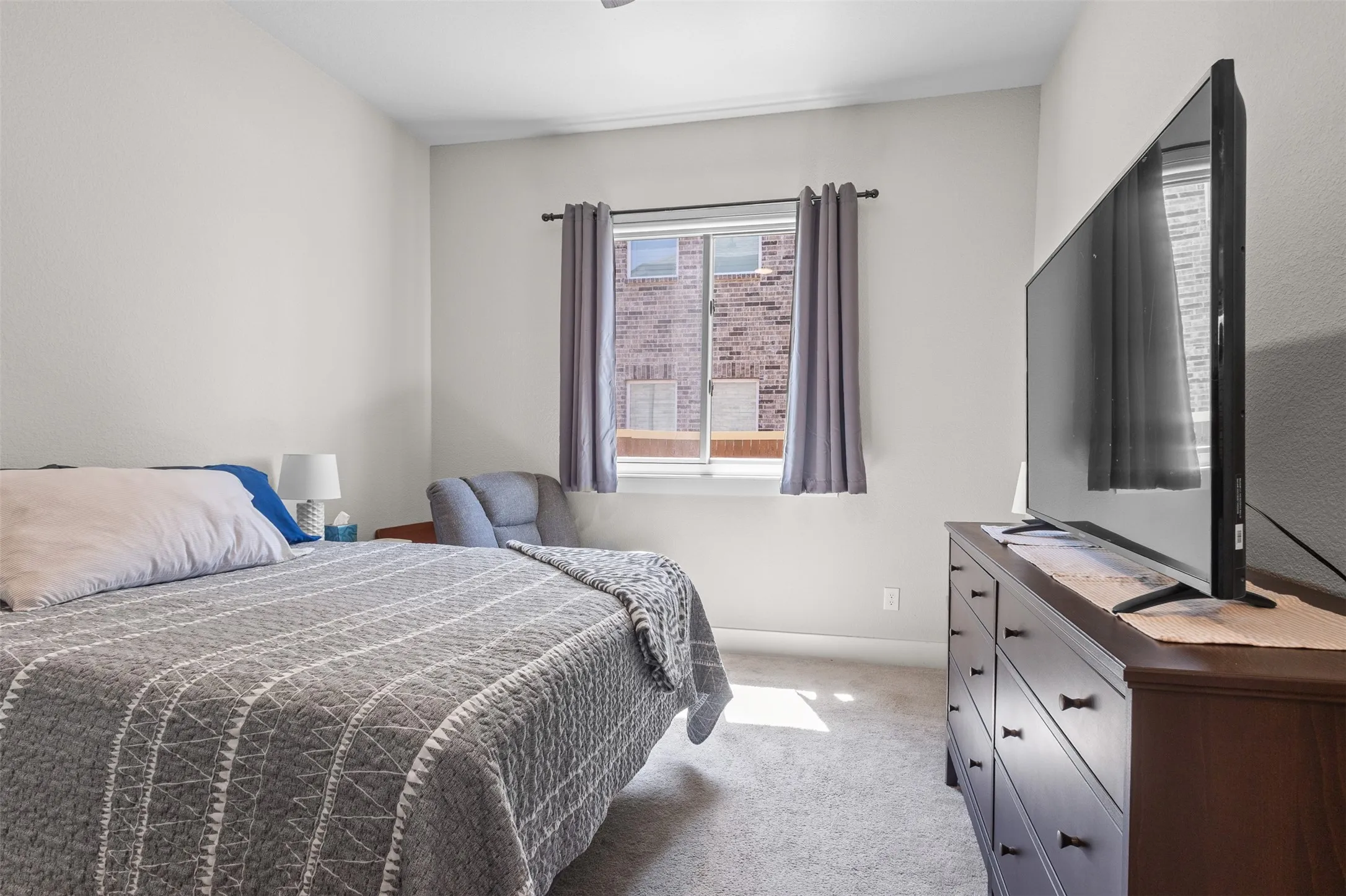 Carpeted flooring, white walls, and a window with a dark rod