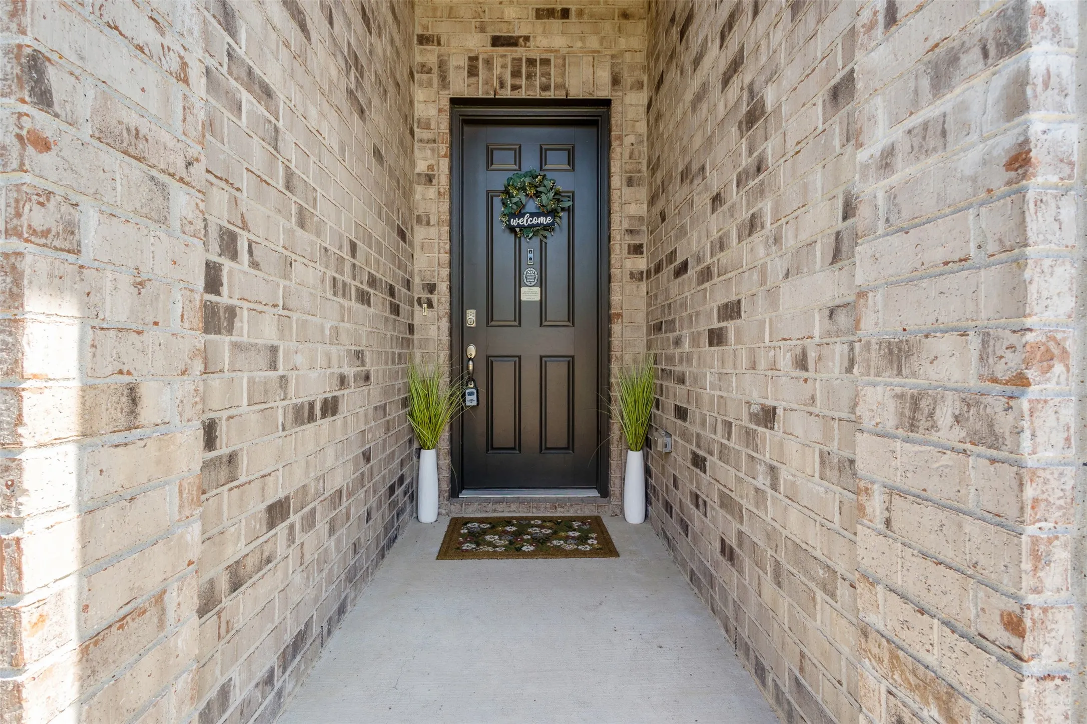 Brick exterior with a paneled entry door and concrete walkway