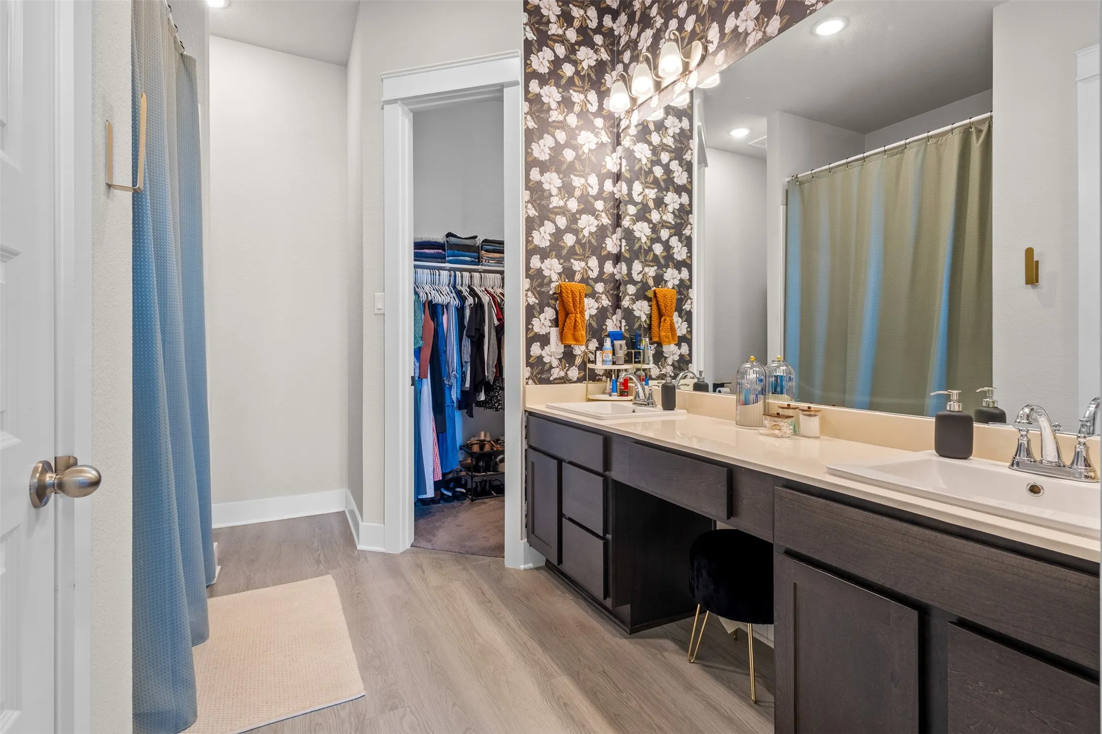 Bathroom featuring dual undermount sinks, an extended vanity with dark wood-finish cabinetry, and wood-finish flooring