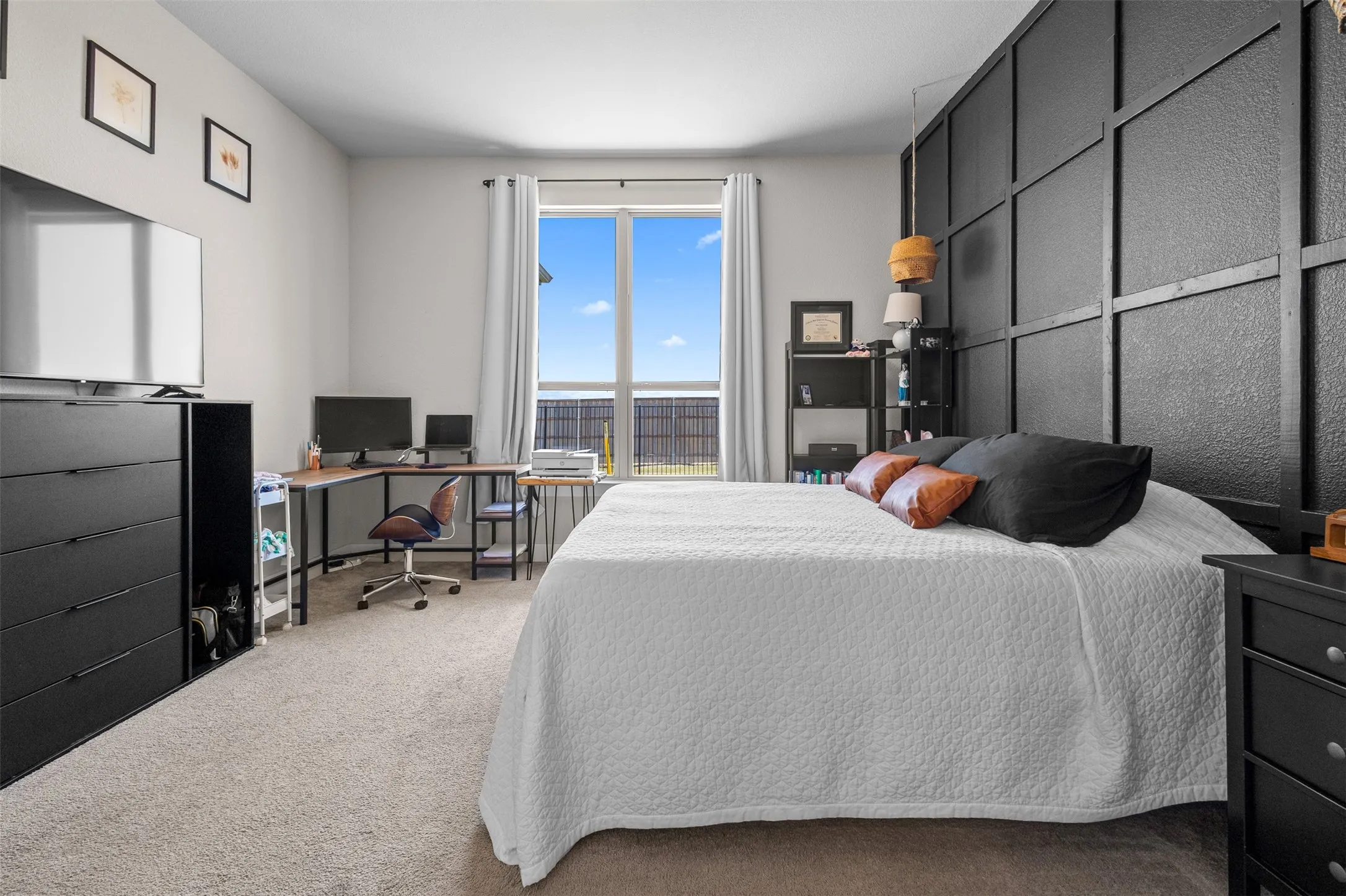 Carpeted room featuring a large window with white drapery, and a dark accent wall with grid detailing