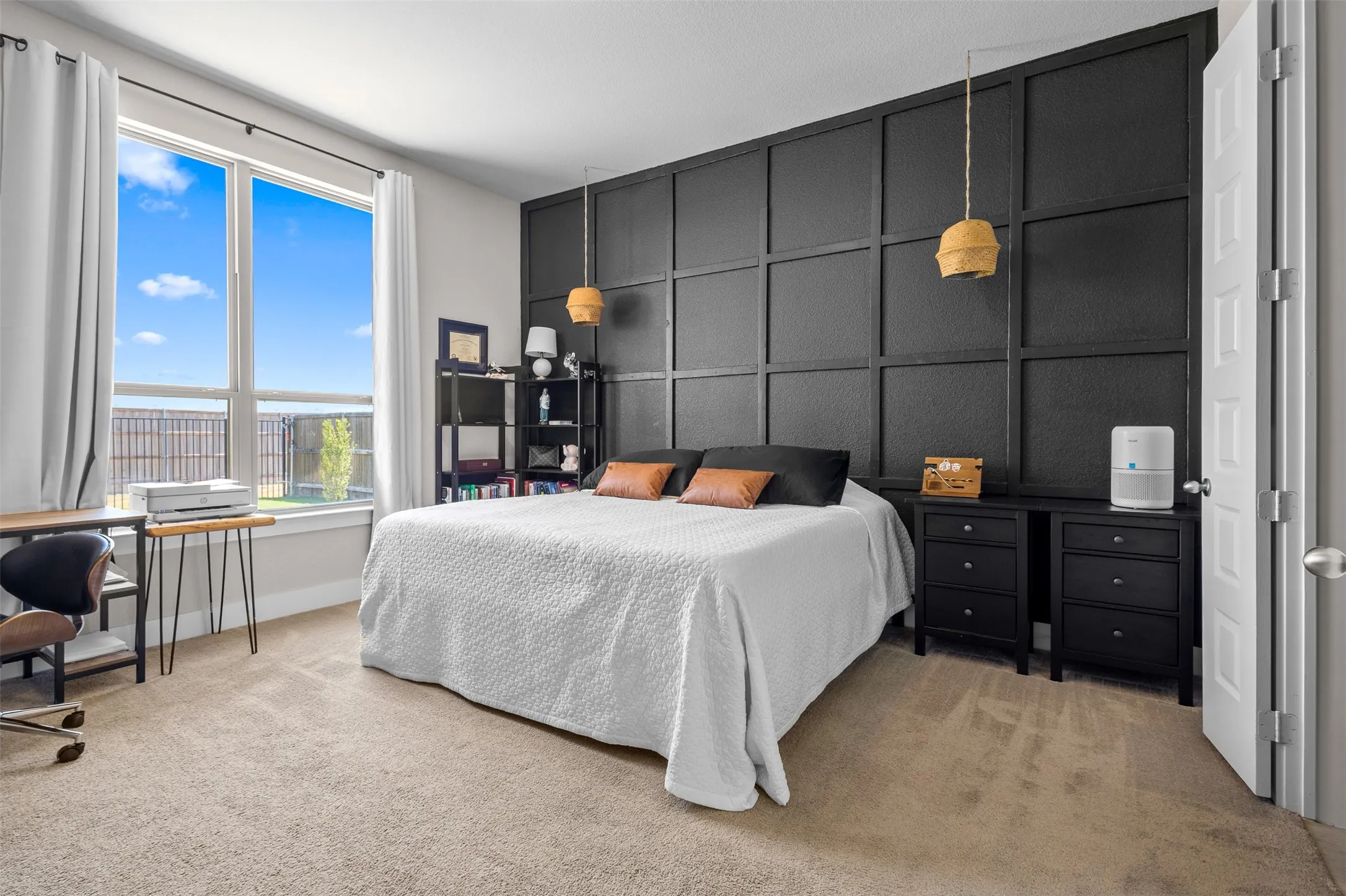 Accent wall with panel molding, large window with ample natural light, light-toned carpet flooring, and a built-in shelving unit
