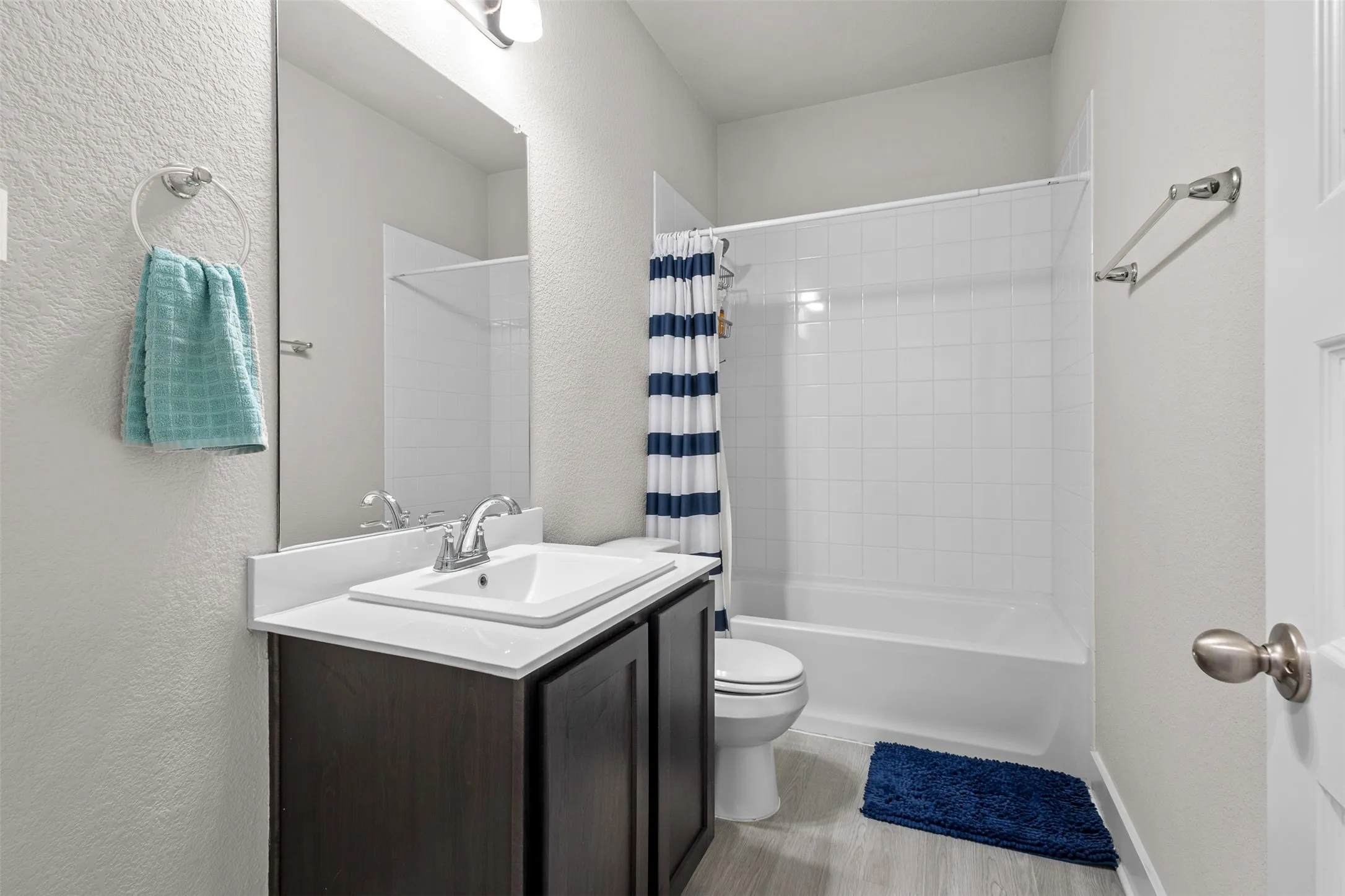 Bathroom featuring a white vanity with an integrated sink, polished chrome faucet, and a large wall-mounted mirror