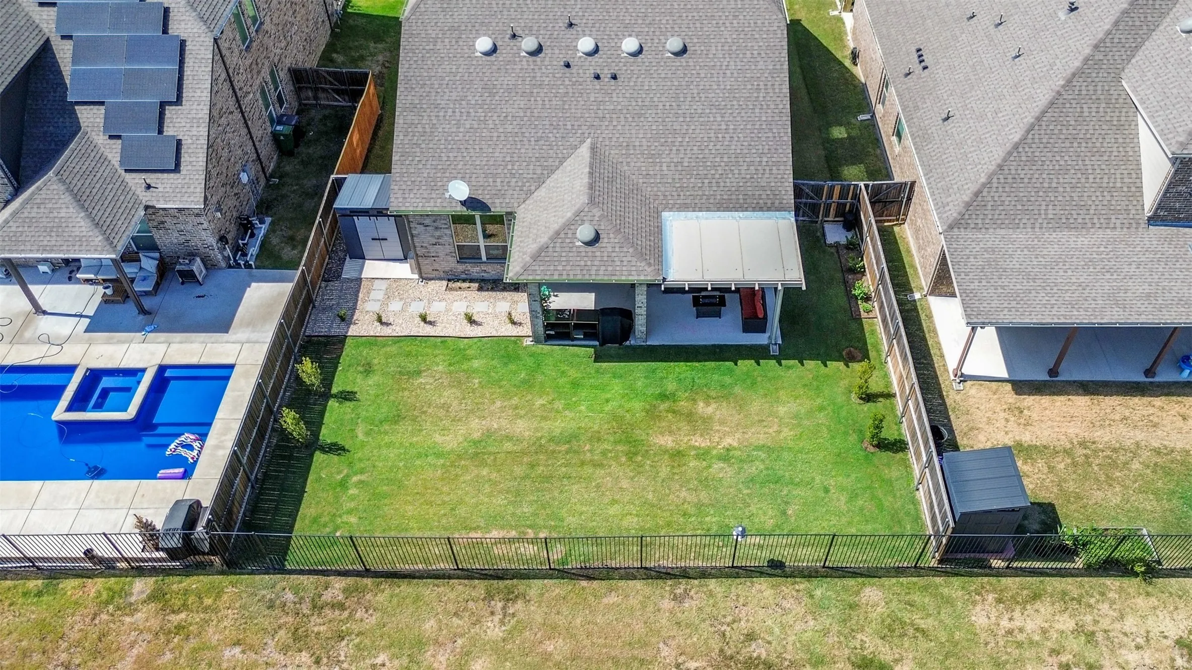 Expansive green lawn with a black metal fence