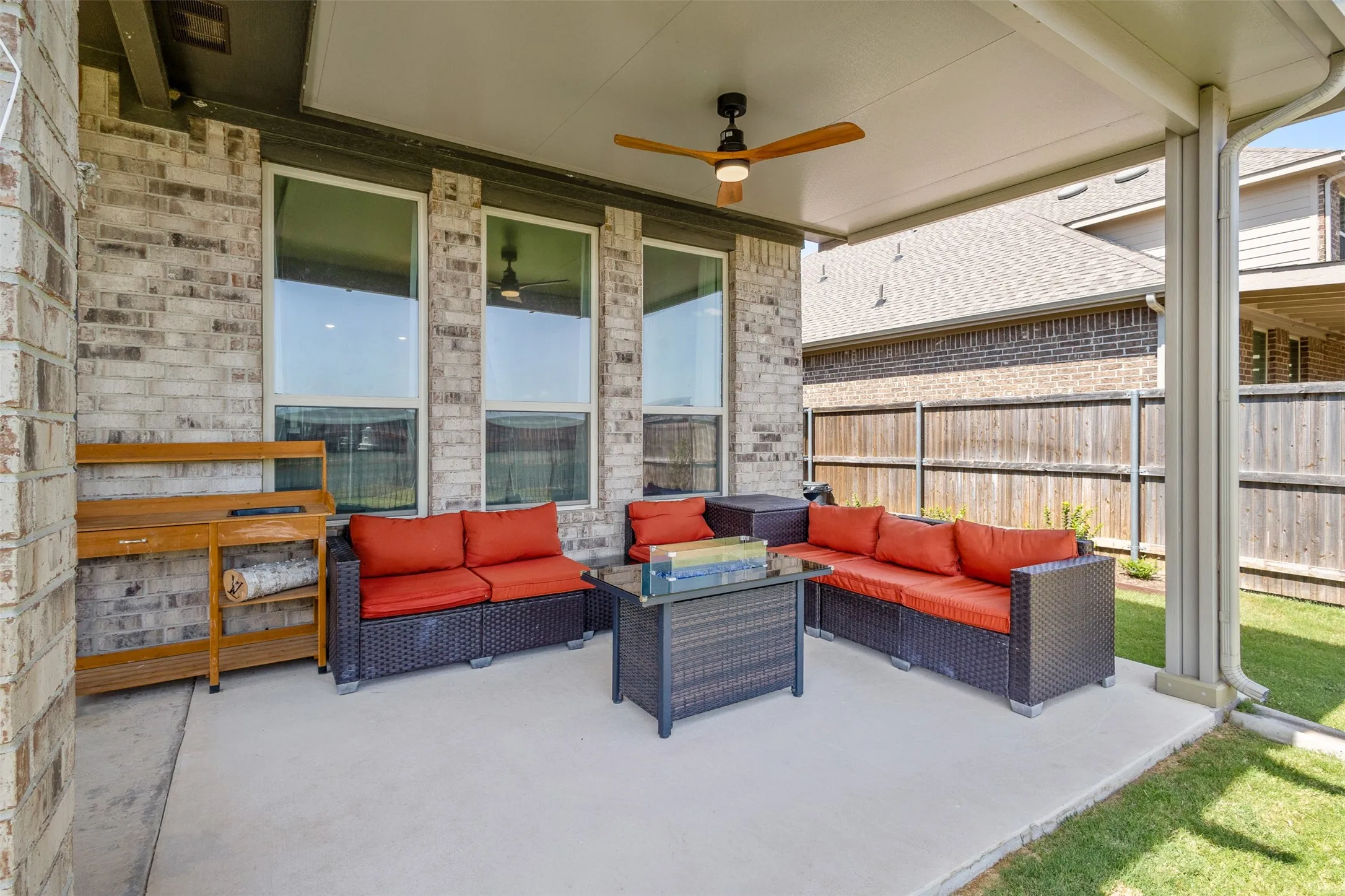 Covered patio featuring a concrete surface, a ceiling fan, and a brick exterior wall
