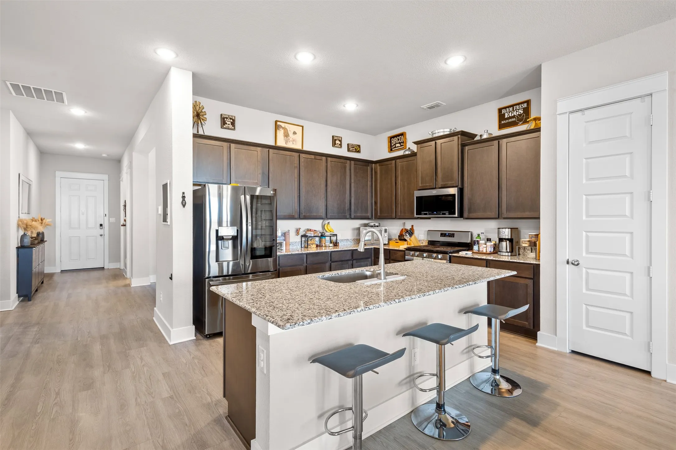 Kitchen featuring dark wood cabinetry, stainless steel appliances, a center island with a stone countertop, and wood-finish flooring