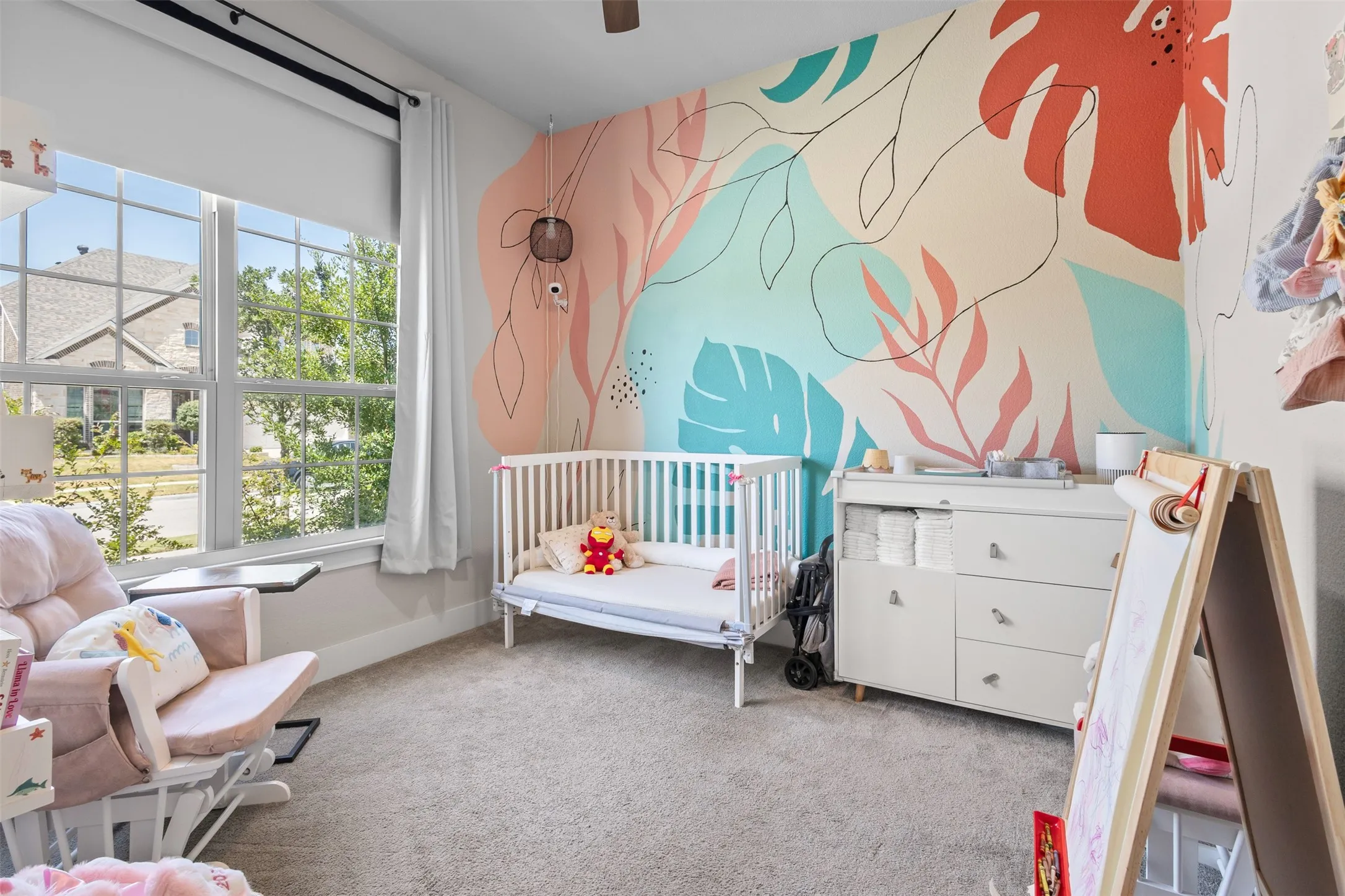 Carpeted room with a ceiling fan, a window with white trim, and a built-in dresser with a changing table surface