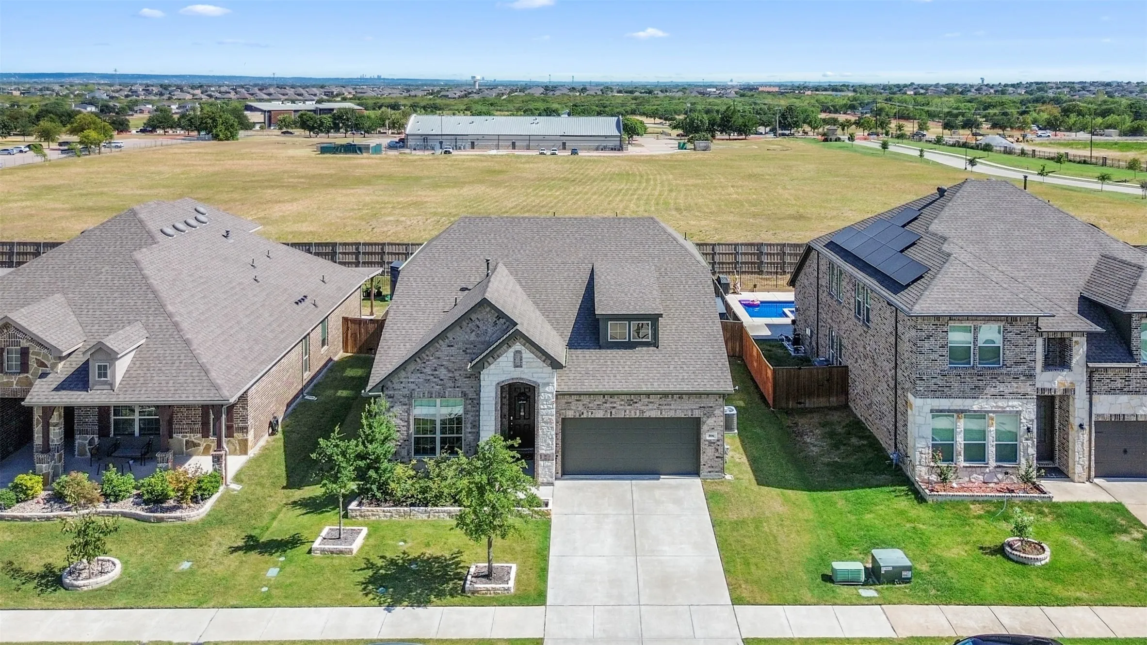 Stone and brick exterior with a front-facing garage, concrete driveway, and established landscaping