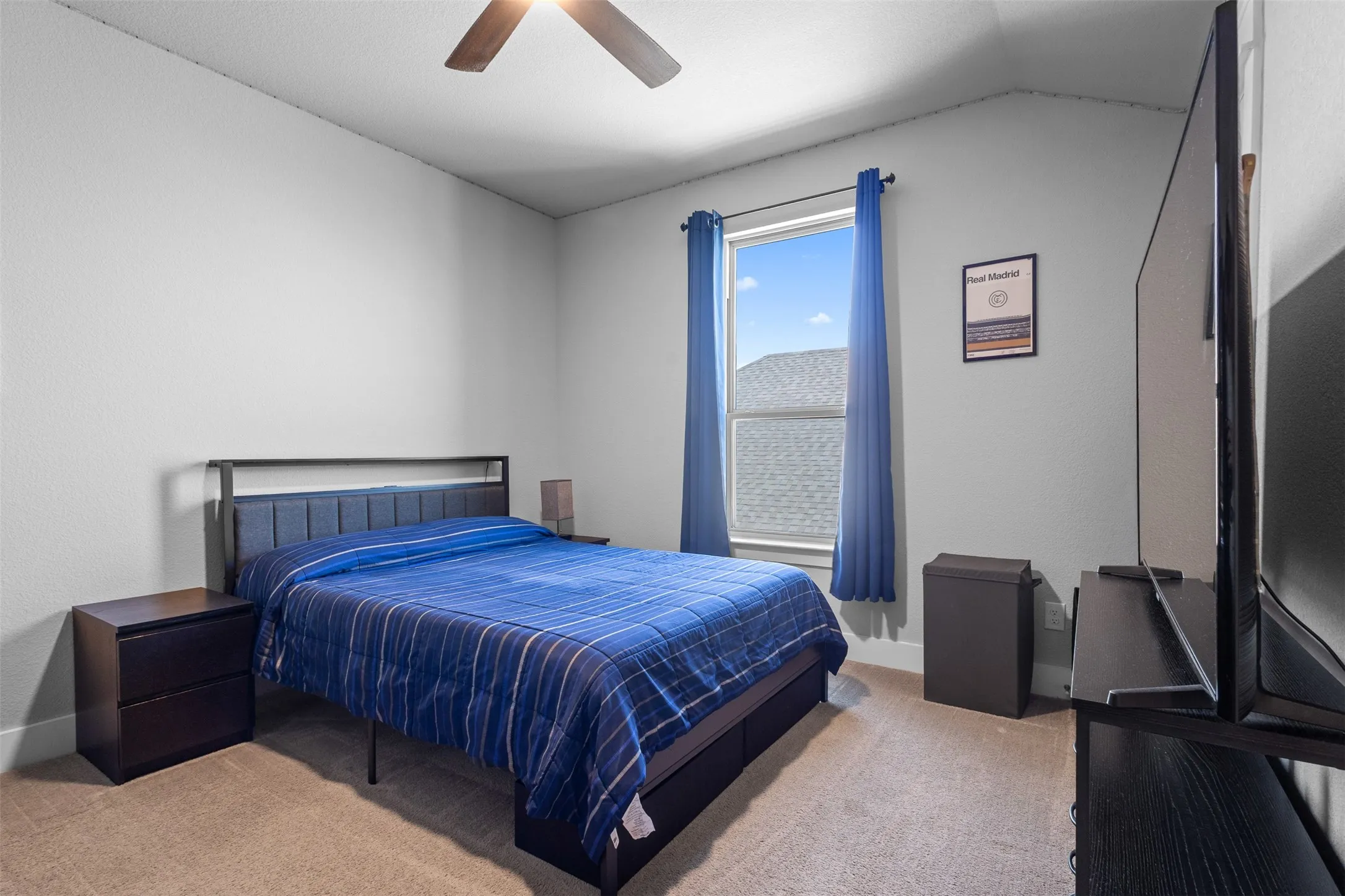 Vaulted ceiling with a ceiling fan, window with curtains, and carpeting throughout