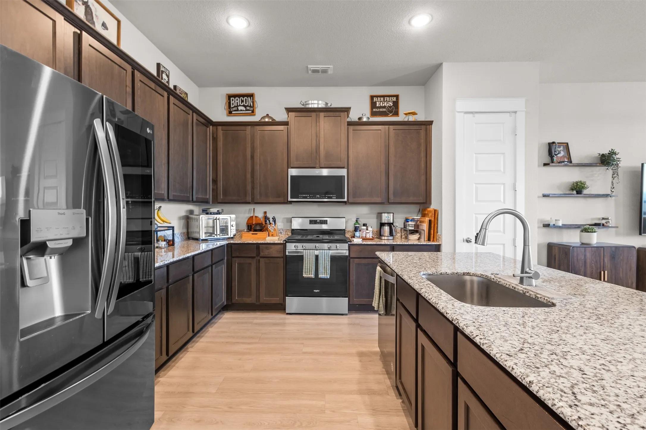 Stainless steel appliances, wood-finish flooring, recessed lighting, and granite countertops