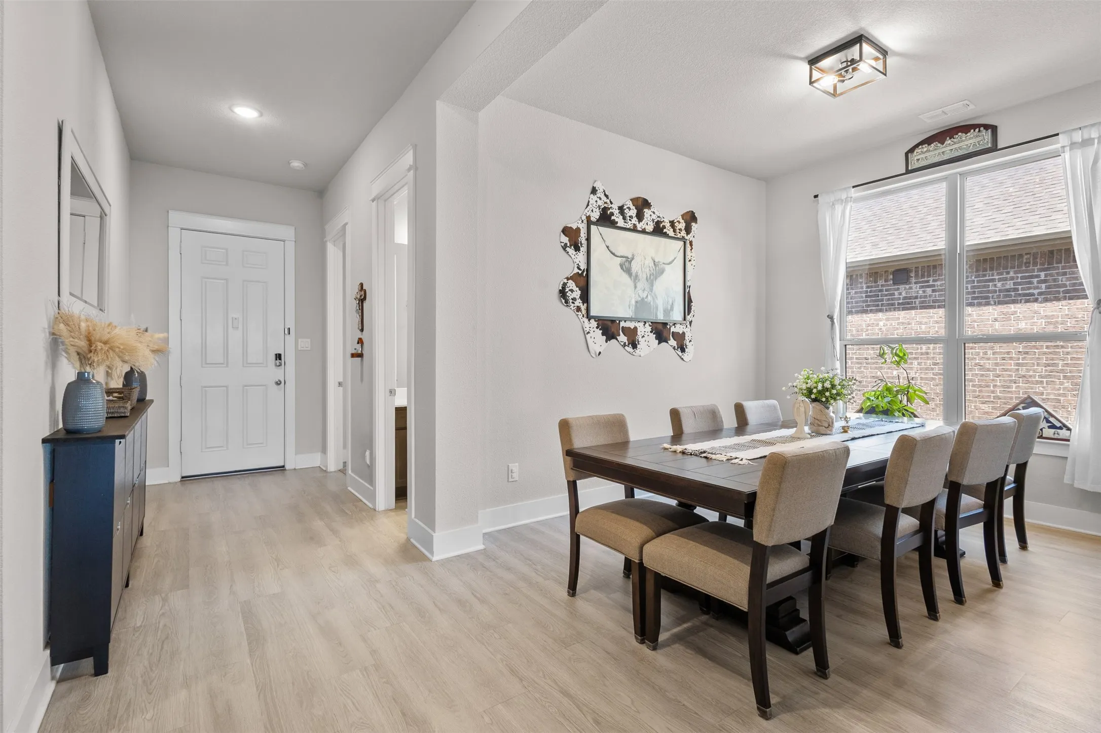 Light wood-finish flooring throughout, recessed ceiling lighting, and a front entry door with panel detailing