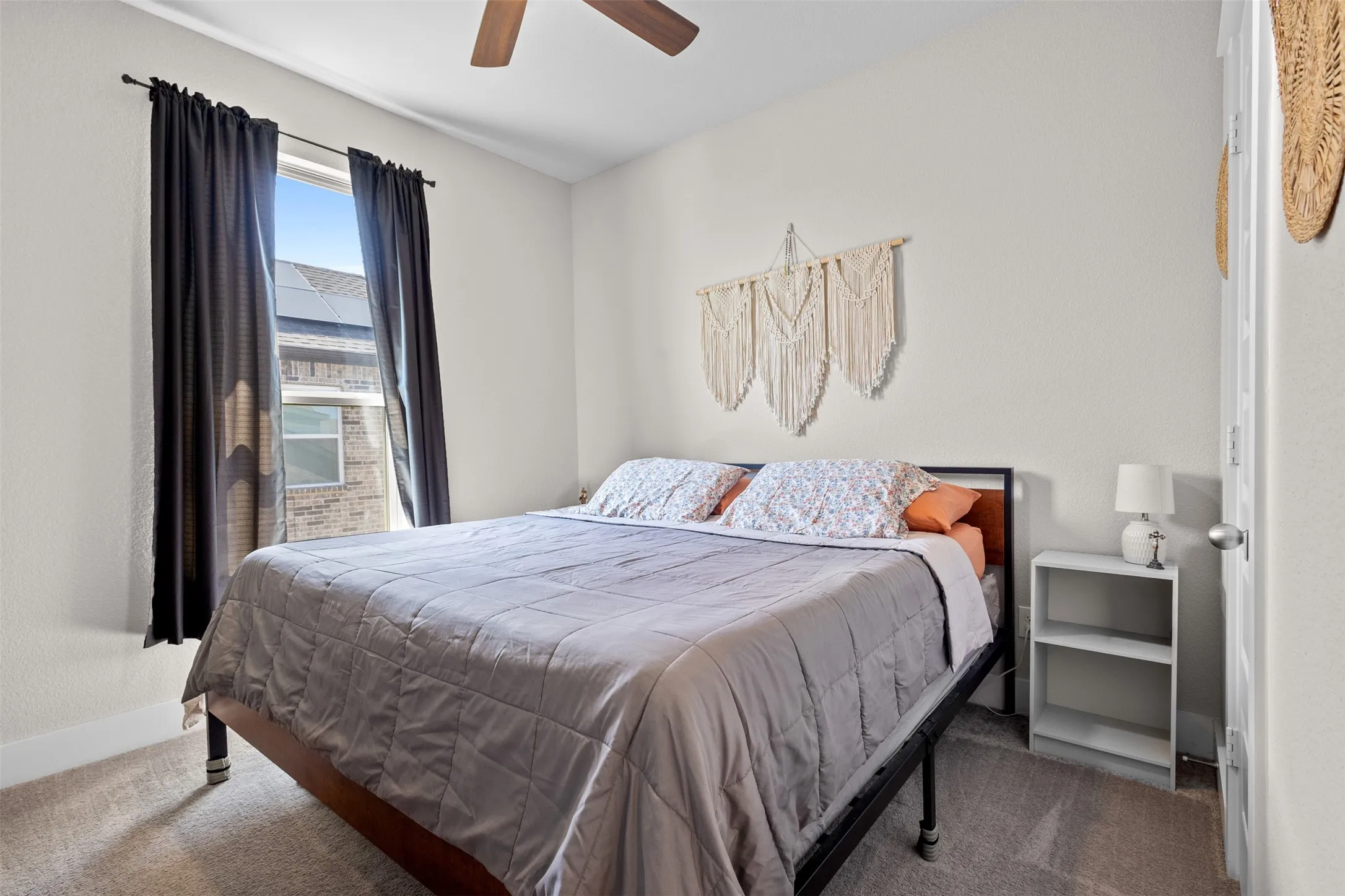 Carpeted room featuring a ceiling fan, a window with dark curtains, and light-colored walls