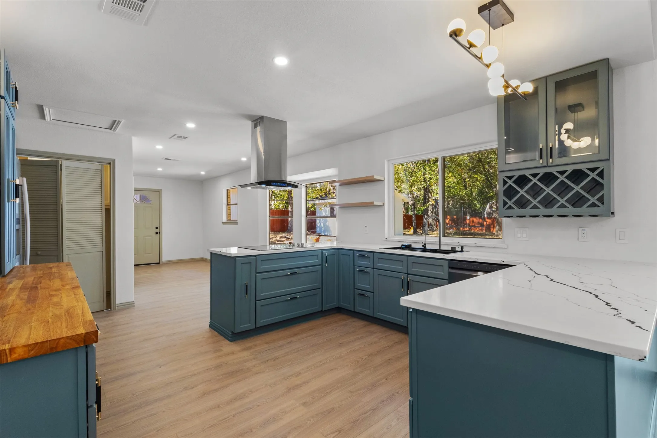 Kitchen featuring a peninsula, hanging light fixtures, recessed lighting, light wood-style flooring, and light stone countertops