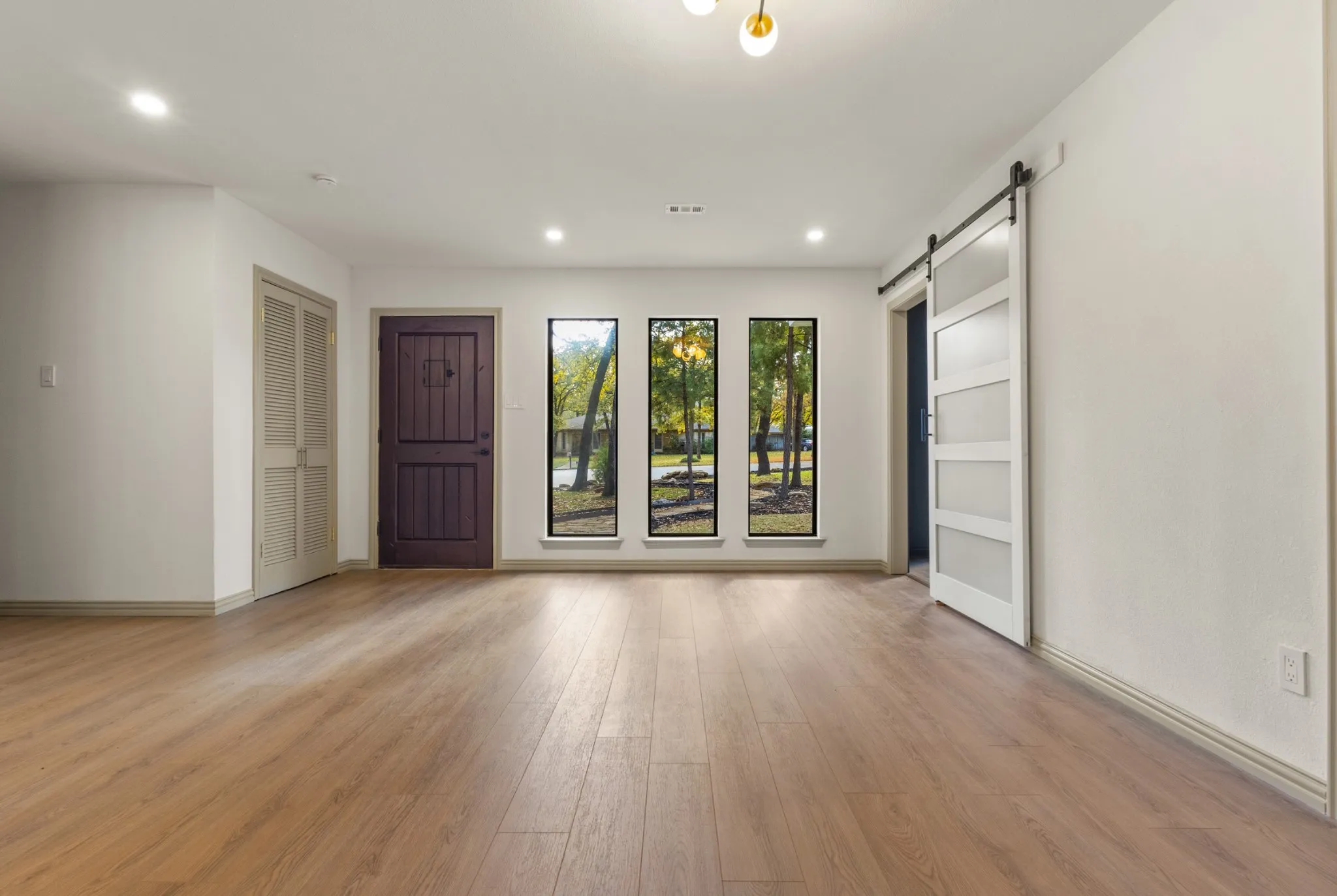Unfurnished room with a barn door, light wood-style flooring, and recessed lighting