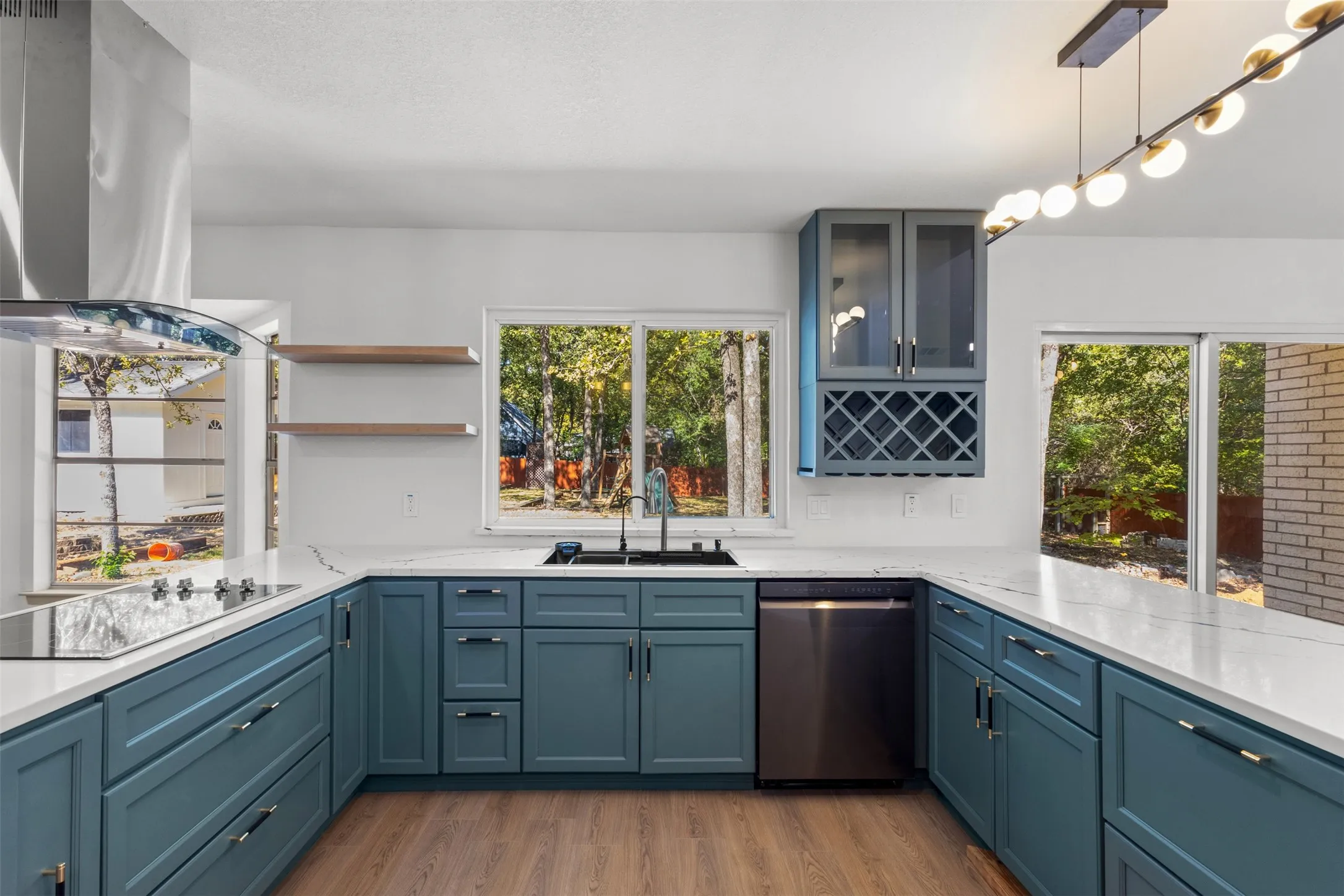 Kitchen with extractor fan, dishwasher, light stone counters, light wood finished floors, and glass insert cabinets