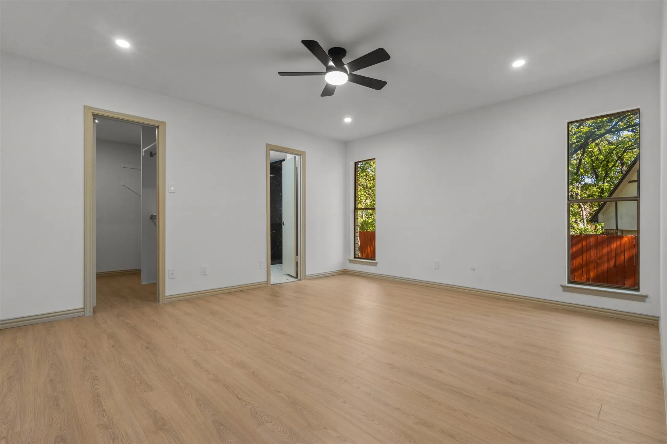 Unfurnished bedroom with a walk in closet, light wood-style floors, ceiling fan, and recessed lighting
