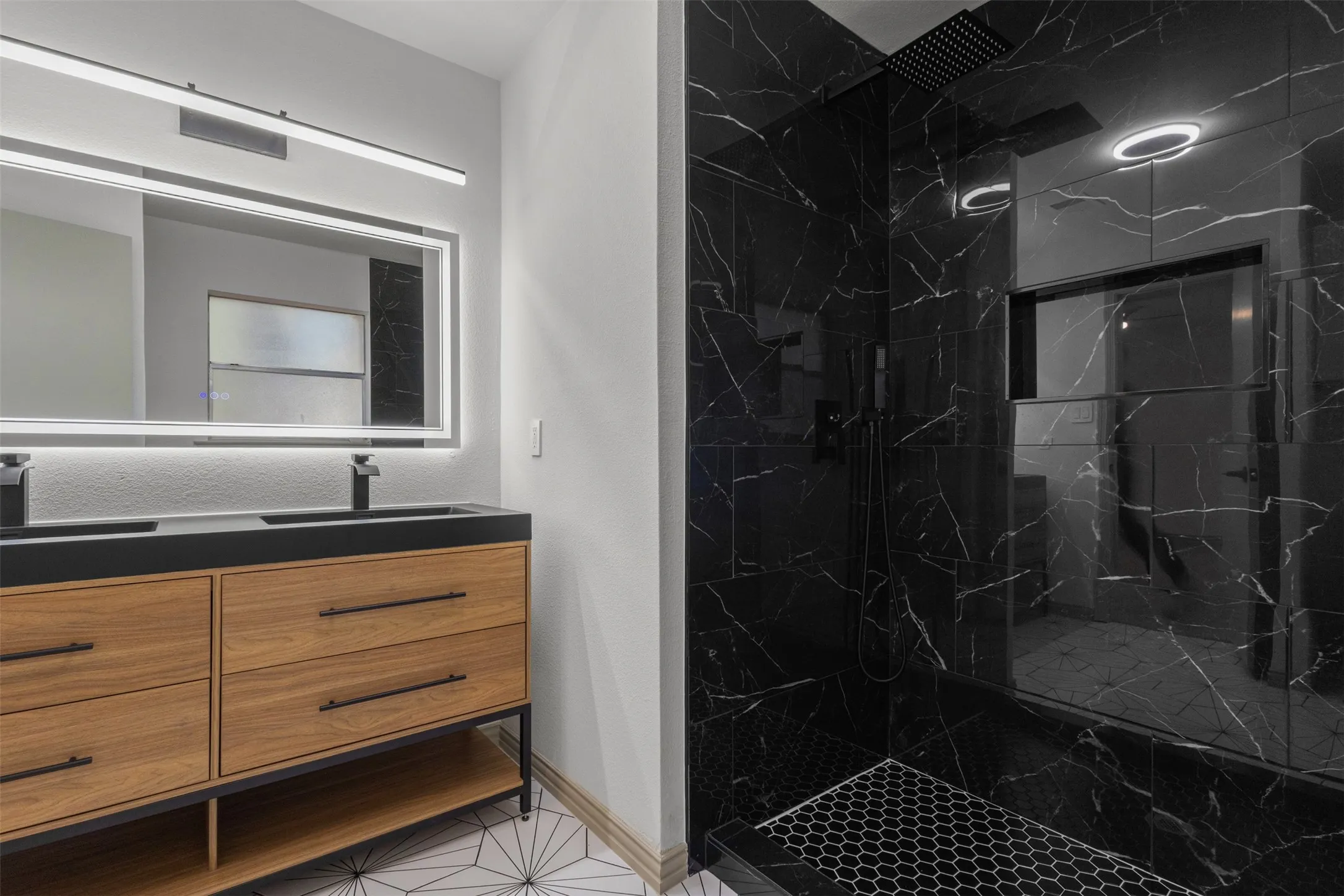 Full bathroom featuring double vanity, a marble finish shower, and light tile patterned floors