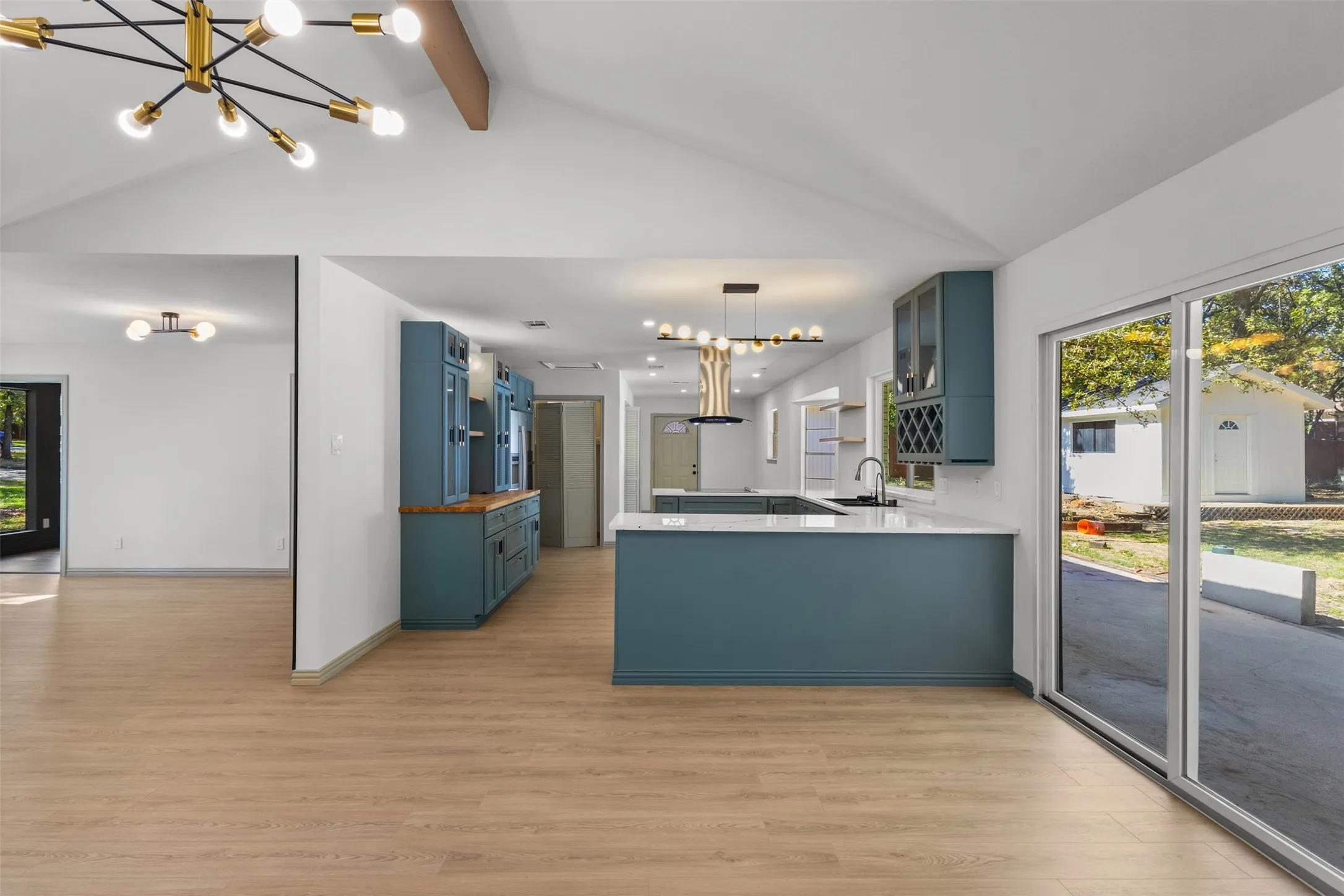 Kitchen with a chandelier, blue cabinets, healthy amount of natural light, and glass insert cabinets