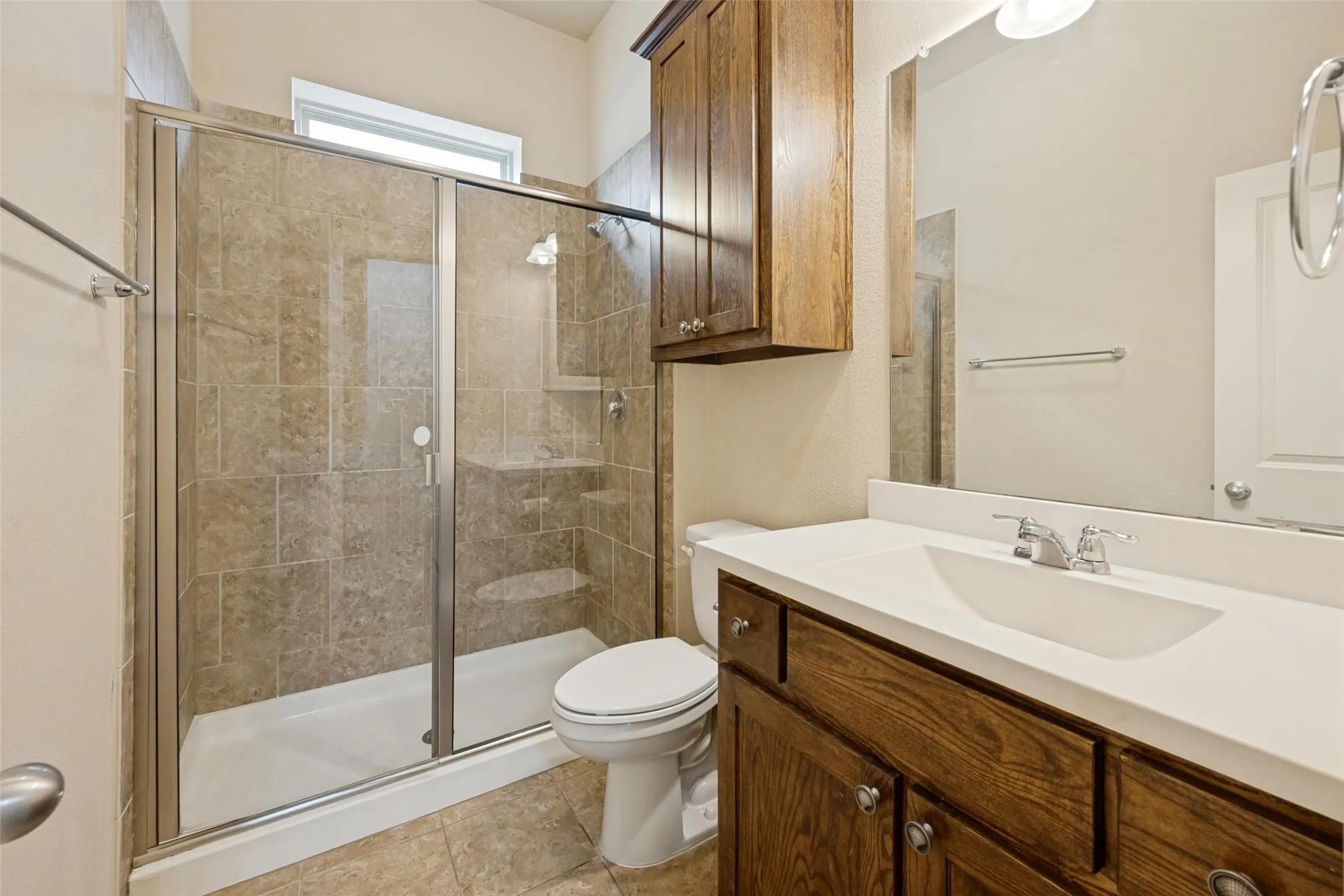 Full bathroom downstairs with Shower with glass enclosure, integrated shelving, and tiled walls