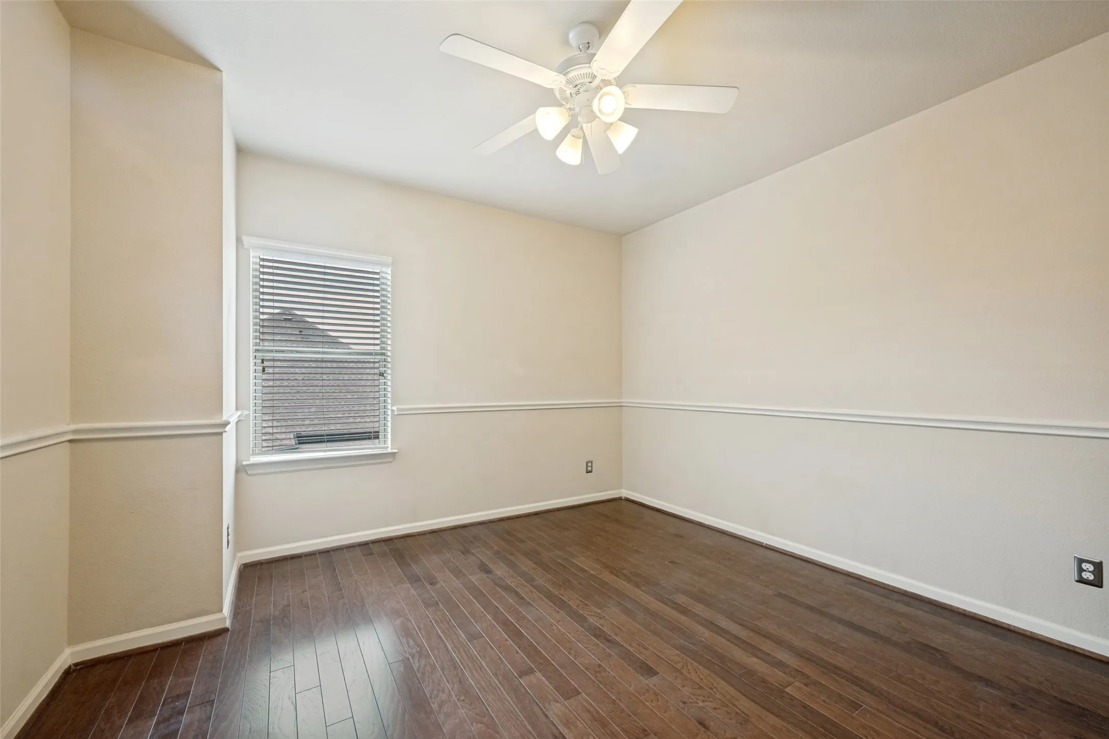Hardwood-style flooring with a natural finish, white ceiling fan with integrated lighting, window with blinds, and white chair rail molding