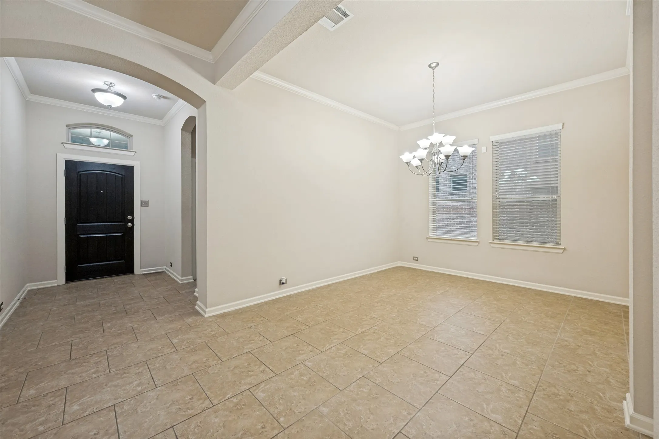 Foyer with a dark wood entry door, arched transom window, and tile flooring