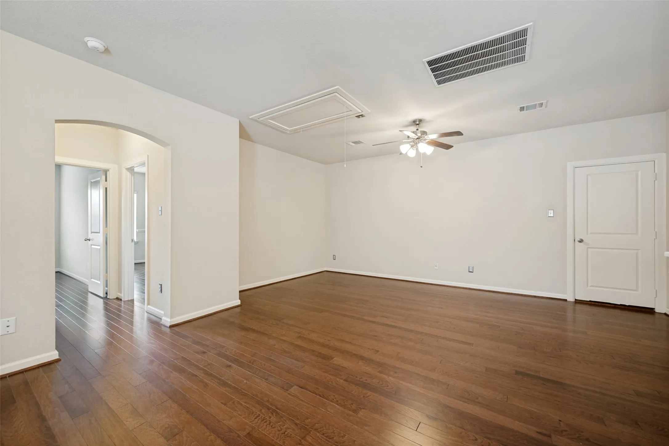 Wood-finish flooring, recessed lighting, ceiling fan, arched doorway, and white paneled doors