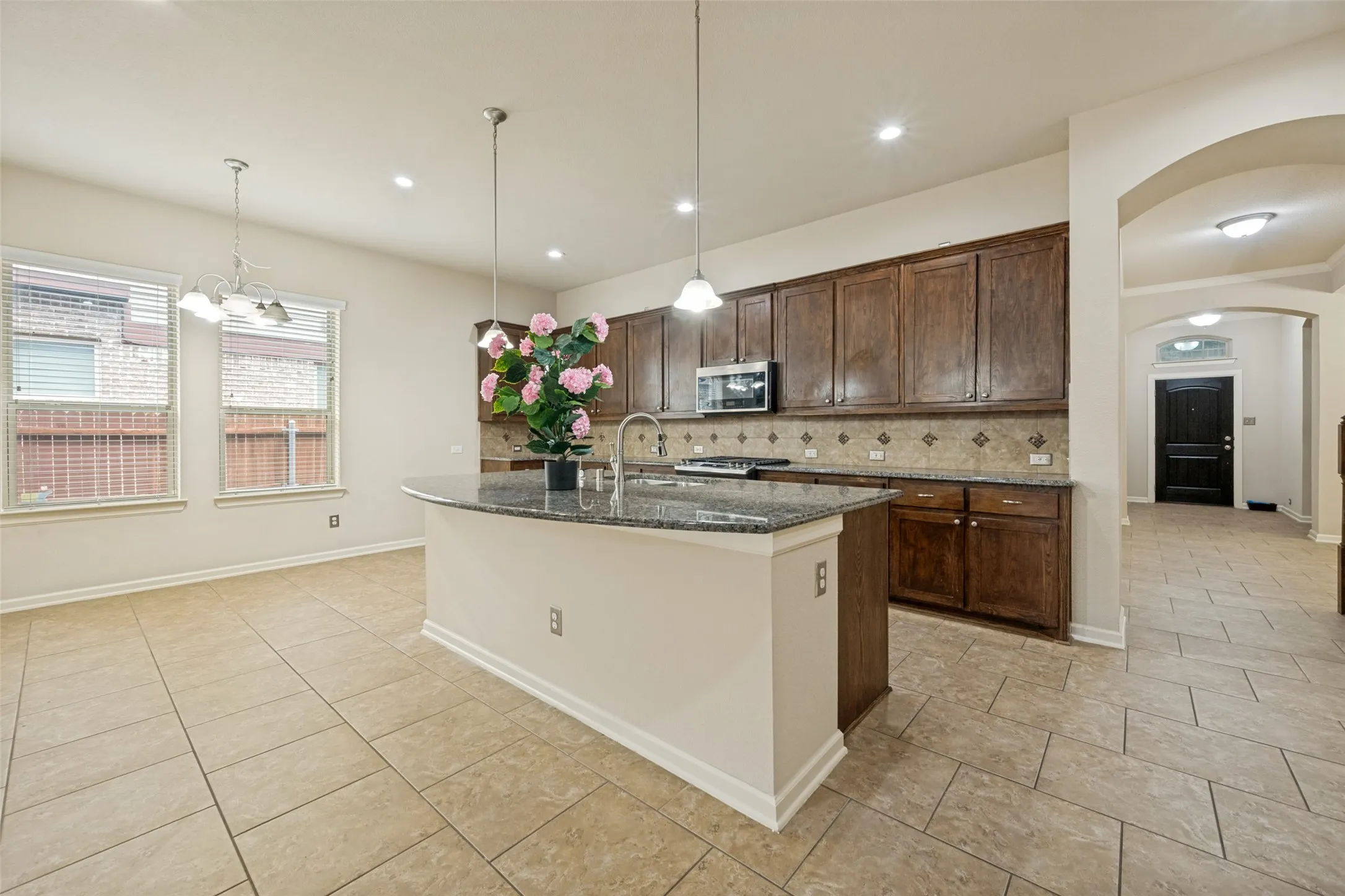 Kitchen featuring an island with a curved countertop, stainless steel appliances, dark wood cabinetry, and tile flooring