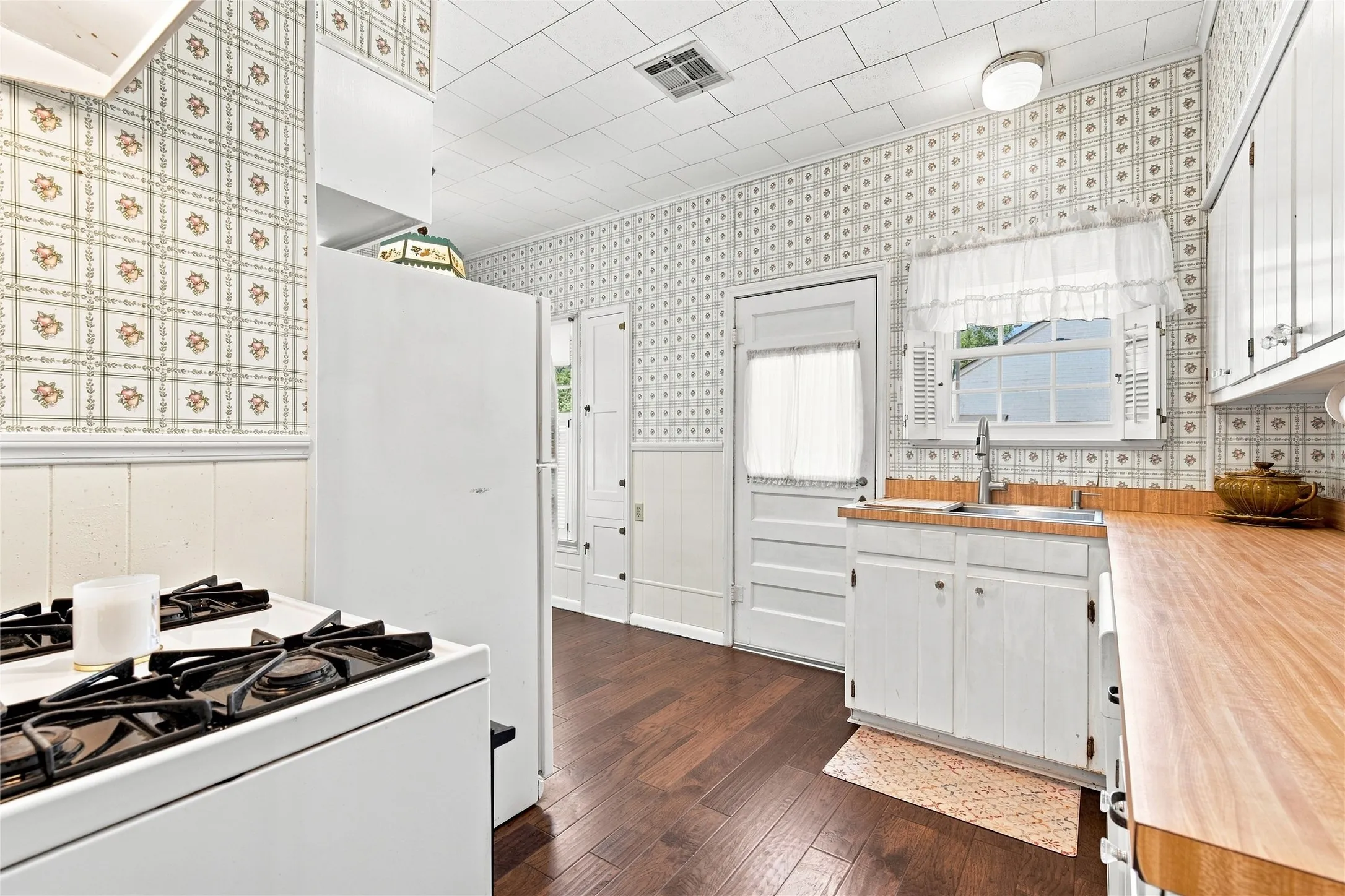 Kitchen with dark wood-finish flooring, white cabinetry, and wood countertops