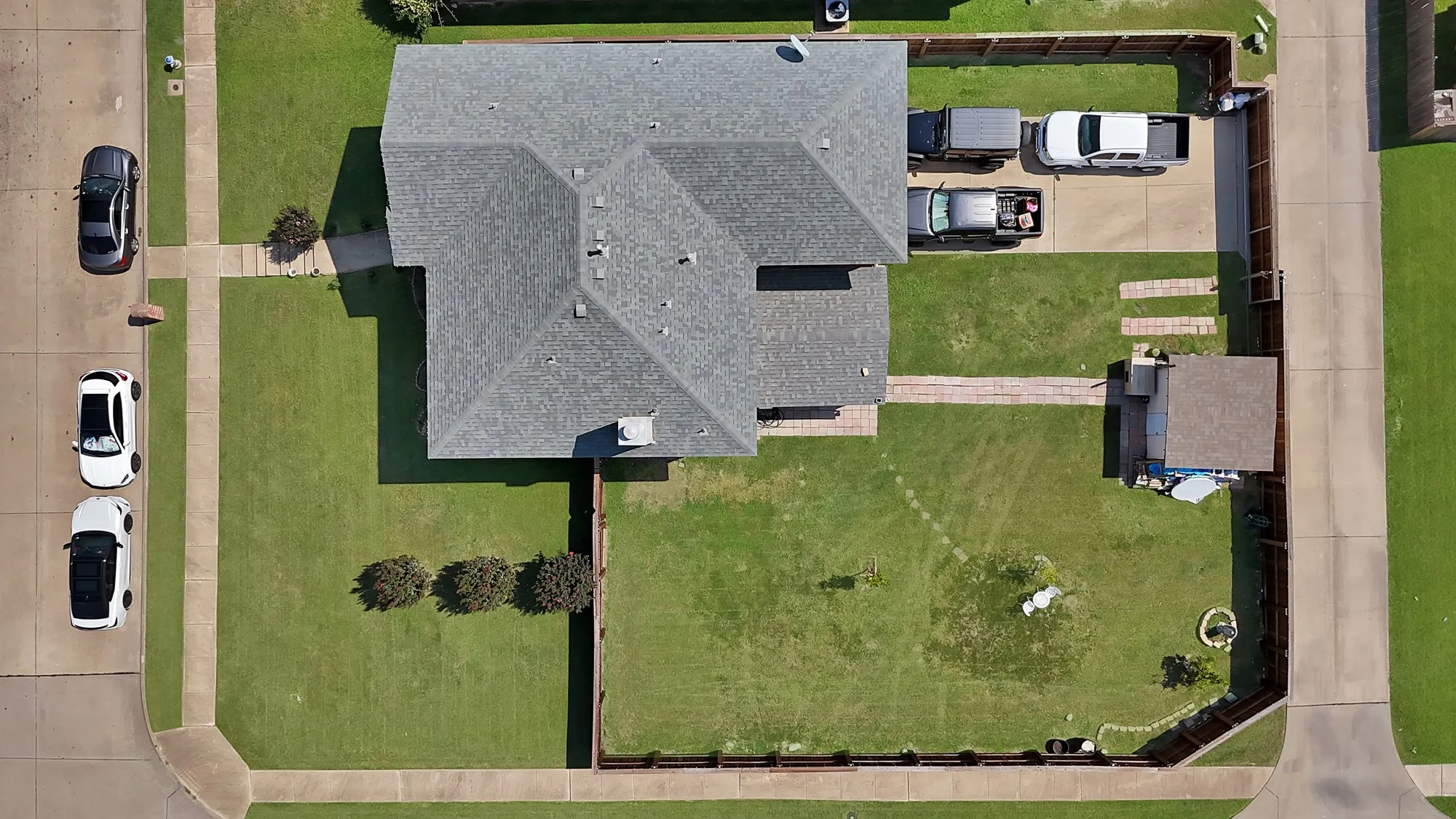 Expansive lot featuring a large lawn area, mature trees, concrete driveway, and a detached structure