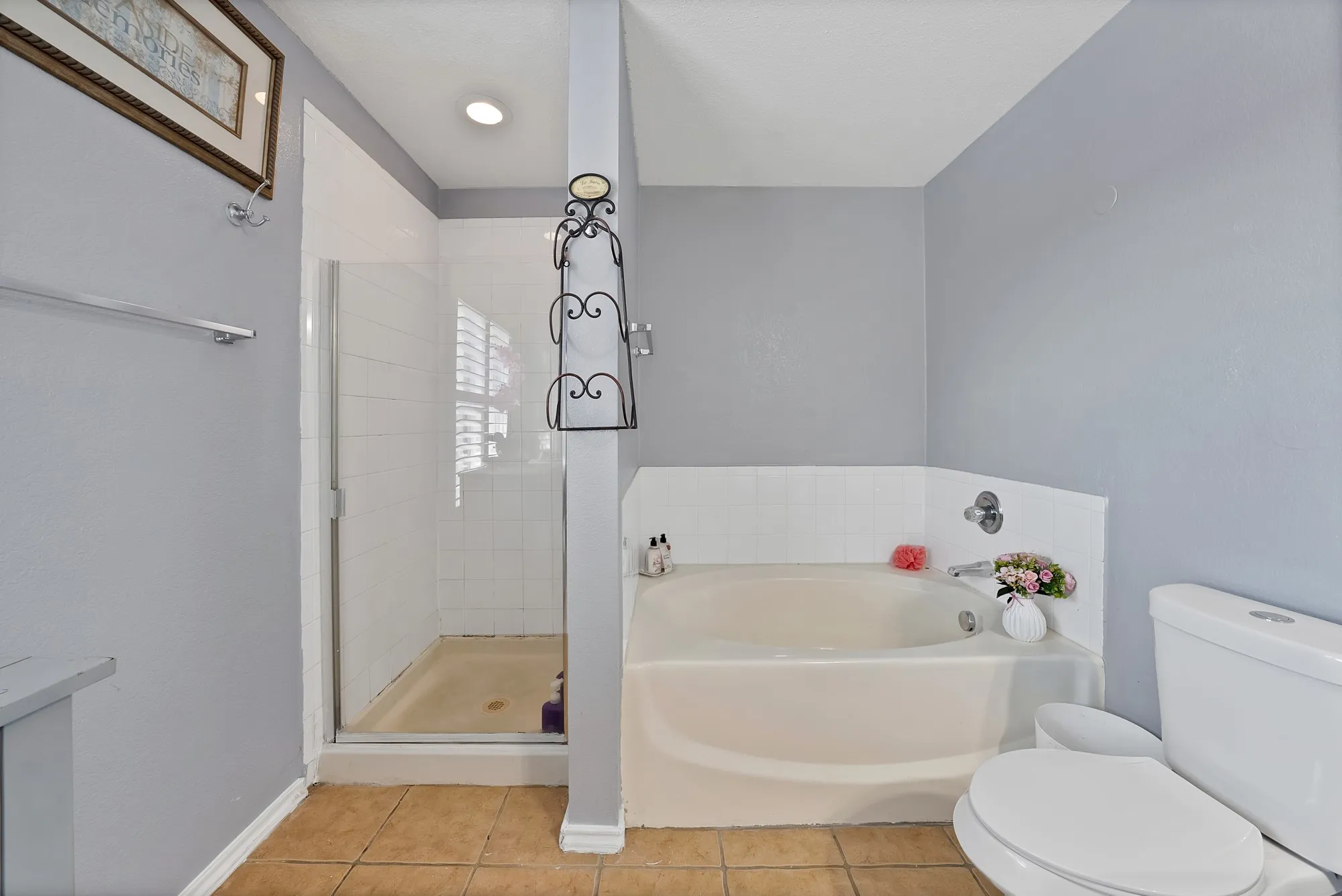 Walk-in shower with clear glass enclosure and tile surround, accompanied by a built-in corner bathtub