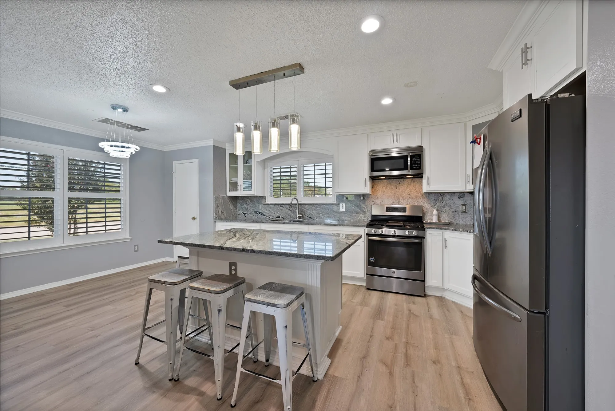 Kitchen featuring a center island with countertop, white cabinetry, stainless steel appliances, and wood-finish flooring