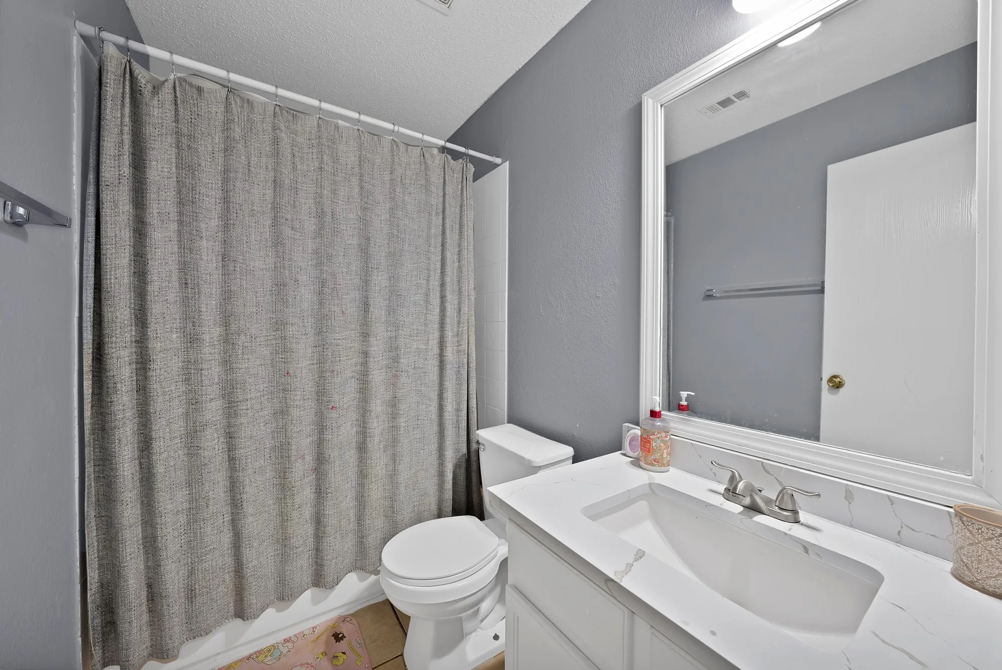 Bathroom featuring a white vanity with an integrated sink, brushed nickel faucet, large framed mirror, and a toilet