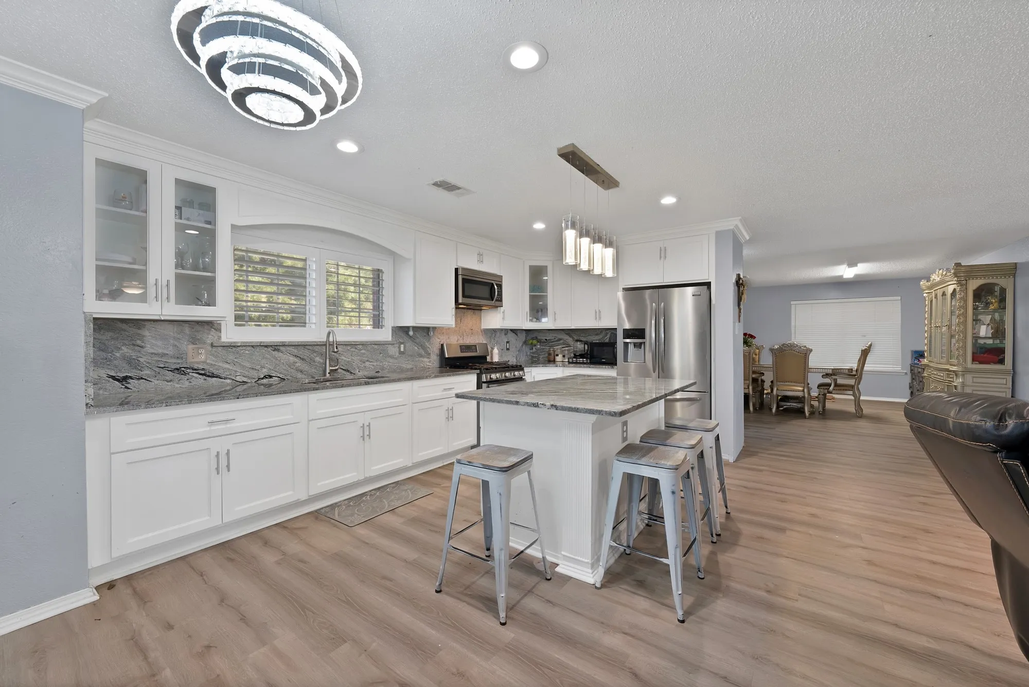 Kitchen featuring white cabinetry, gray stone countertops, a central island with seating, and stainless steel appliances