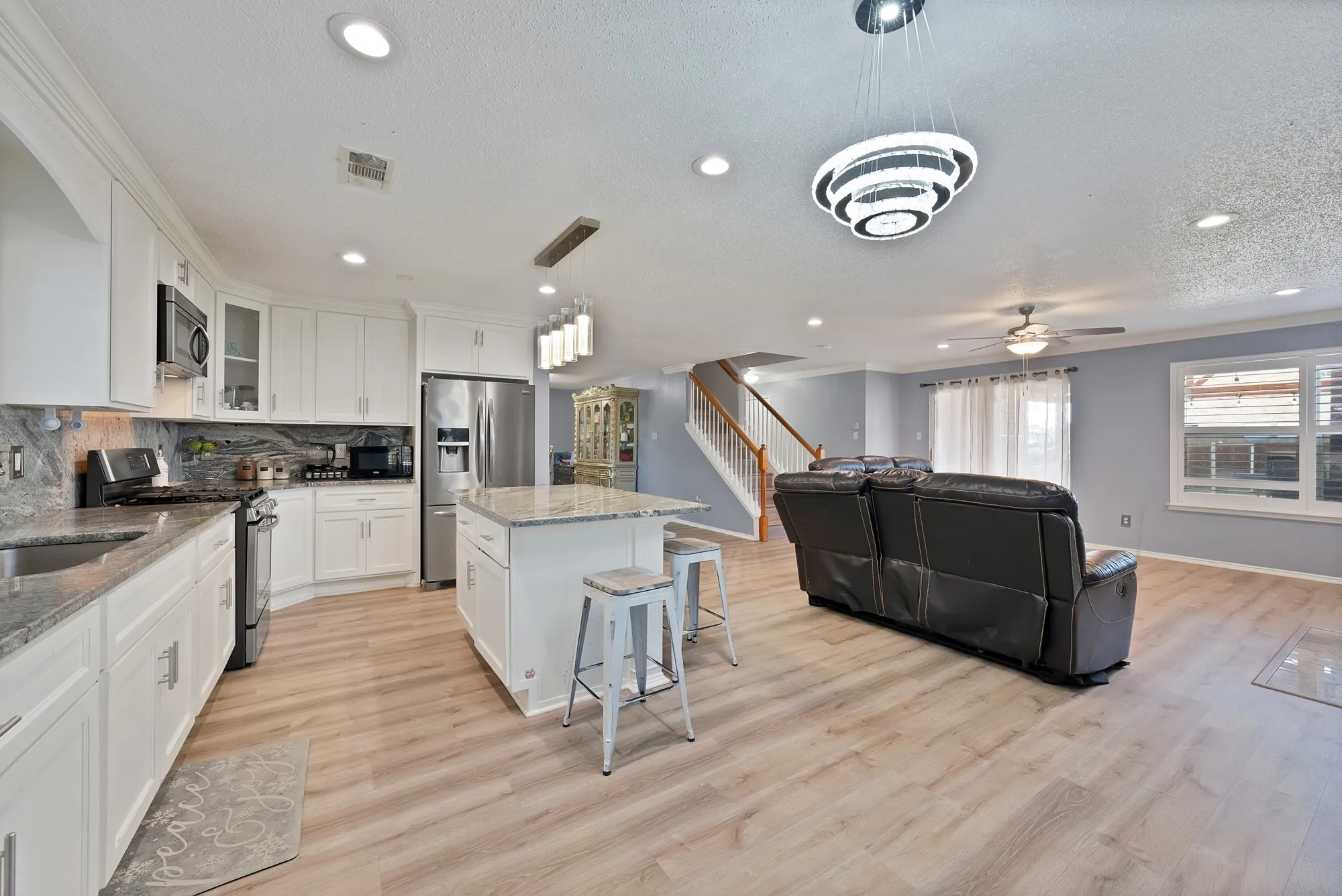 Spacious kitchen featuring white cabinetry, stainless steel appliances, and a central island with countertop seating