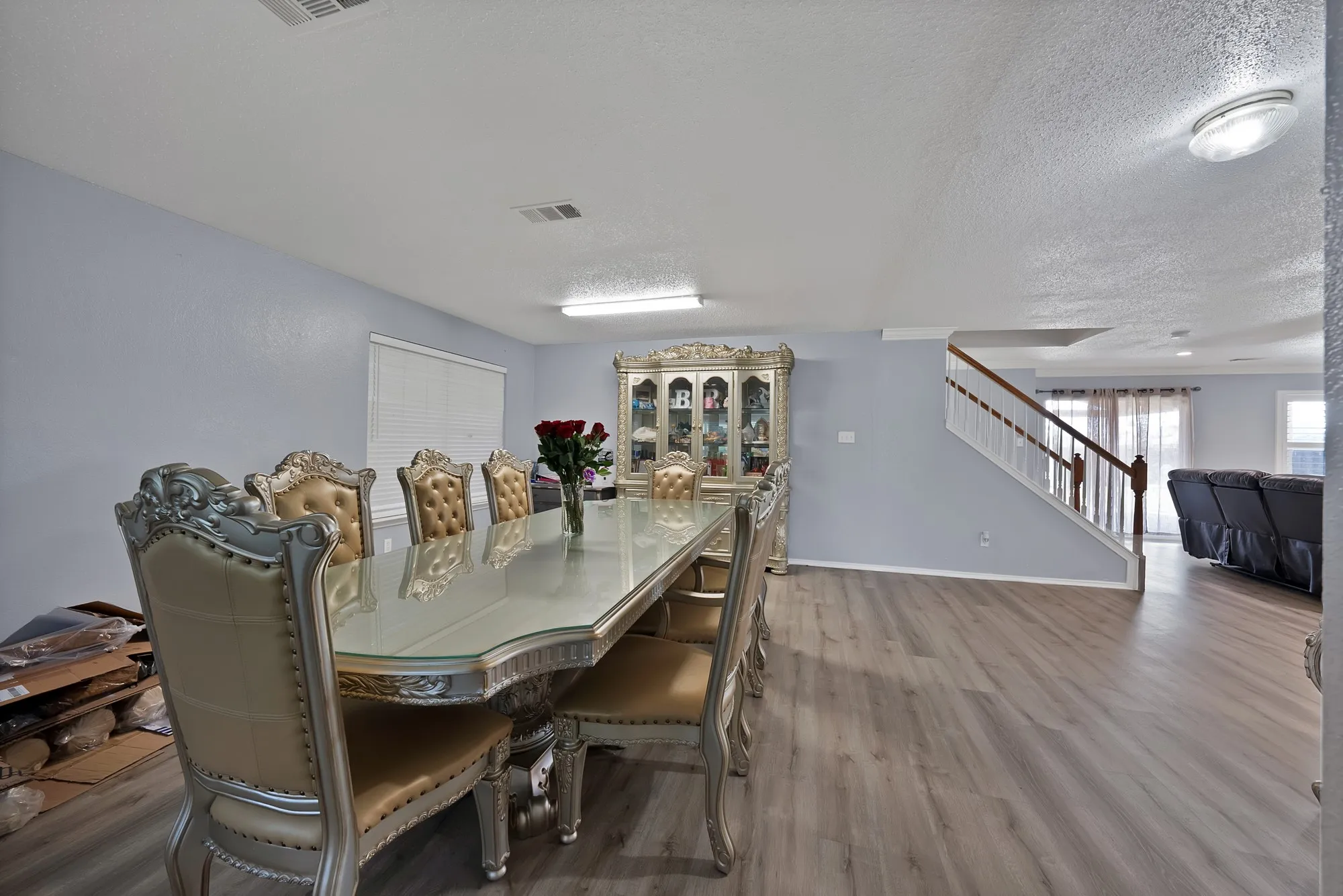 Wood-finish flooring throughout, light gray wall color, white window blinds, and a built-in staircase with white risers and wood-finish handrails