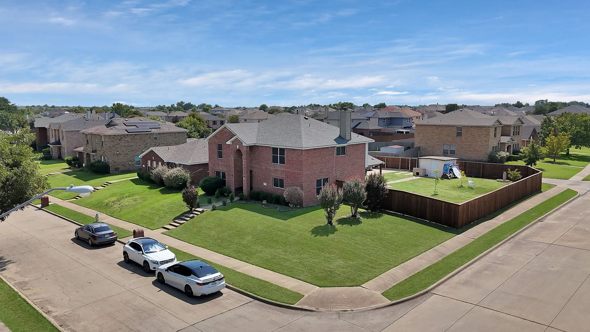 Brick exterior residence with a fenced backyard, mature trees, and a well-maintained lawn