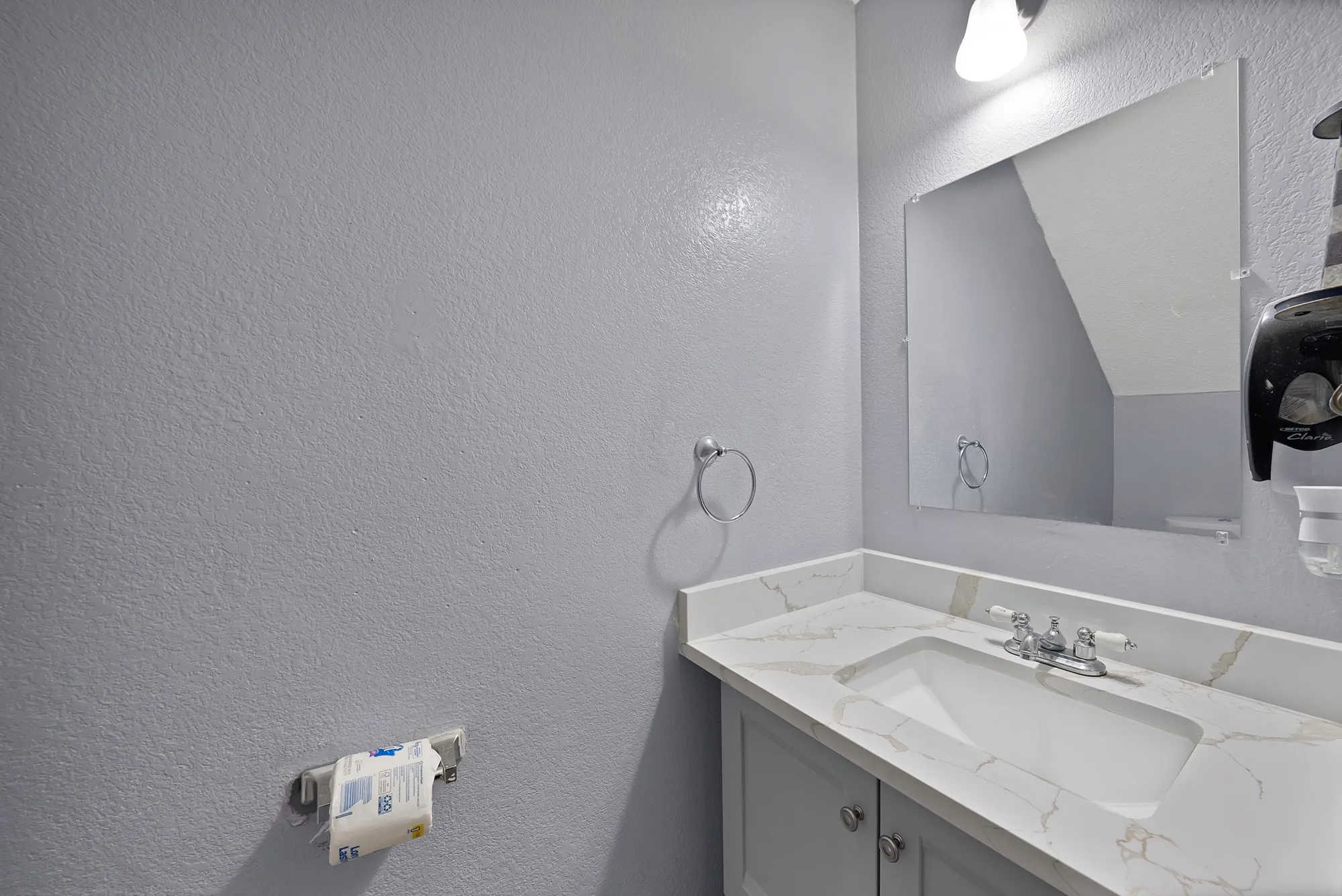 Vanity with an integrated rectangular sink, stone-finish countertop, and chrome faucet