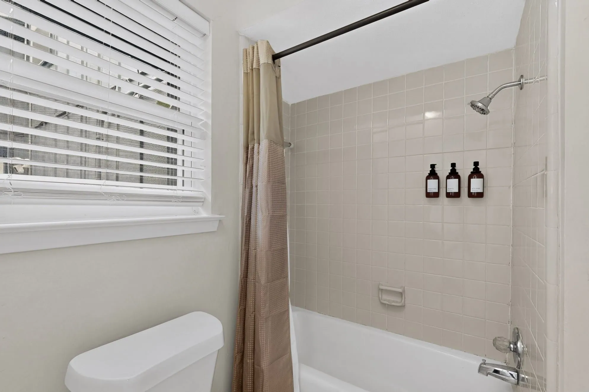 White tiled shower with a chrome showerhead and faucet, featuring a white tub