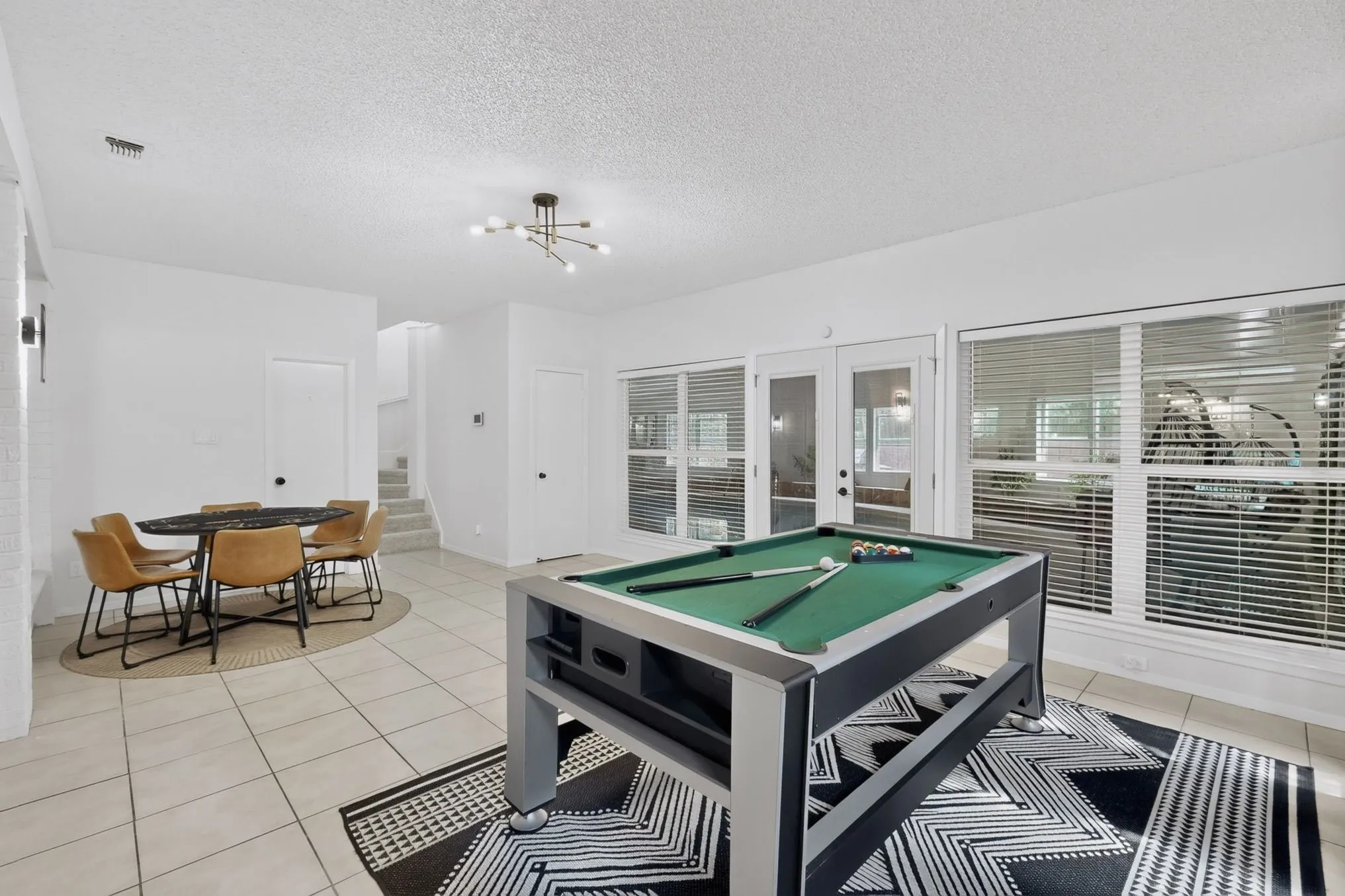Spacious interior with tile flooring, abundant natural light from multiple windows, and a modern ceiling light fixture